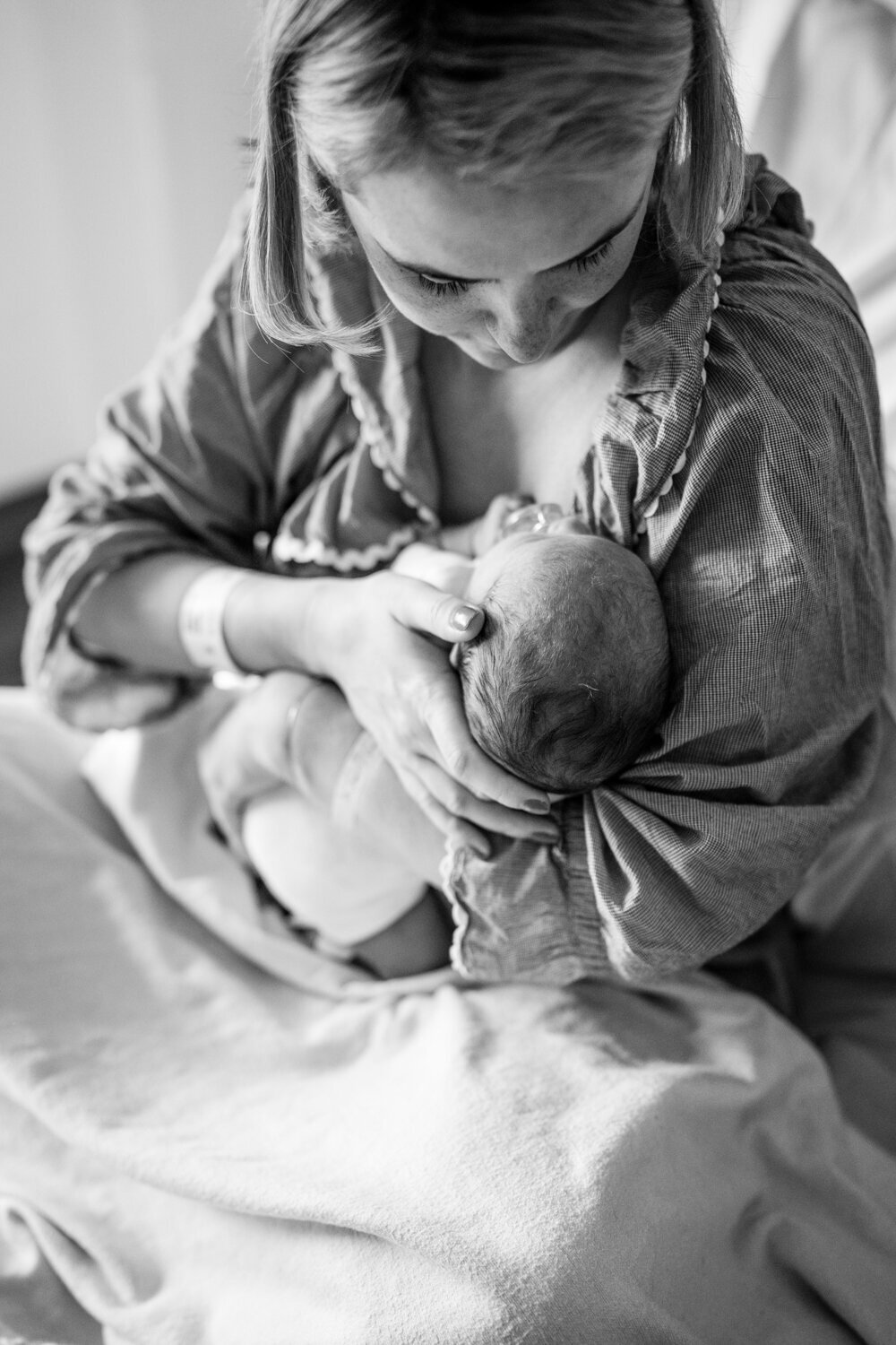 black and white portrait of mother stroking the head of new baby in hospital