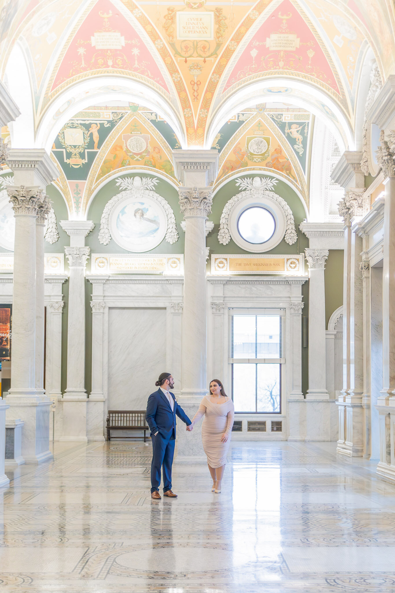 A couple holding hands walks through the Library of Congress in Washington D.C.