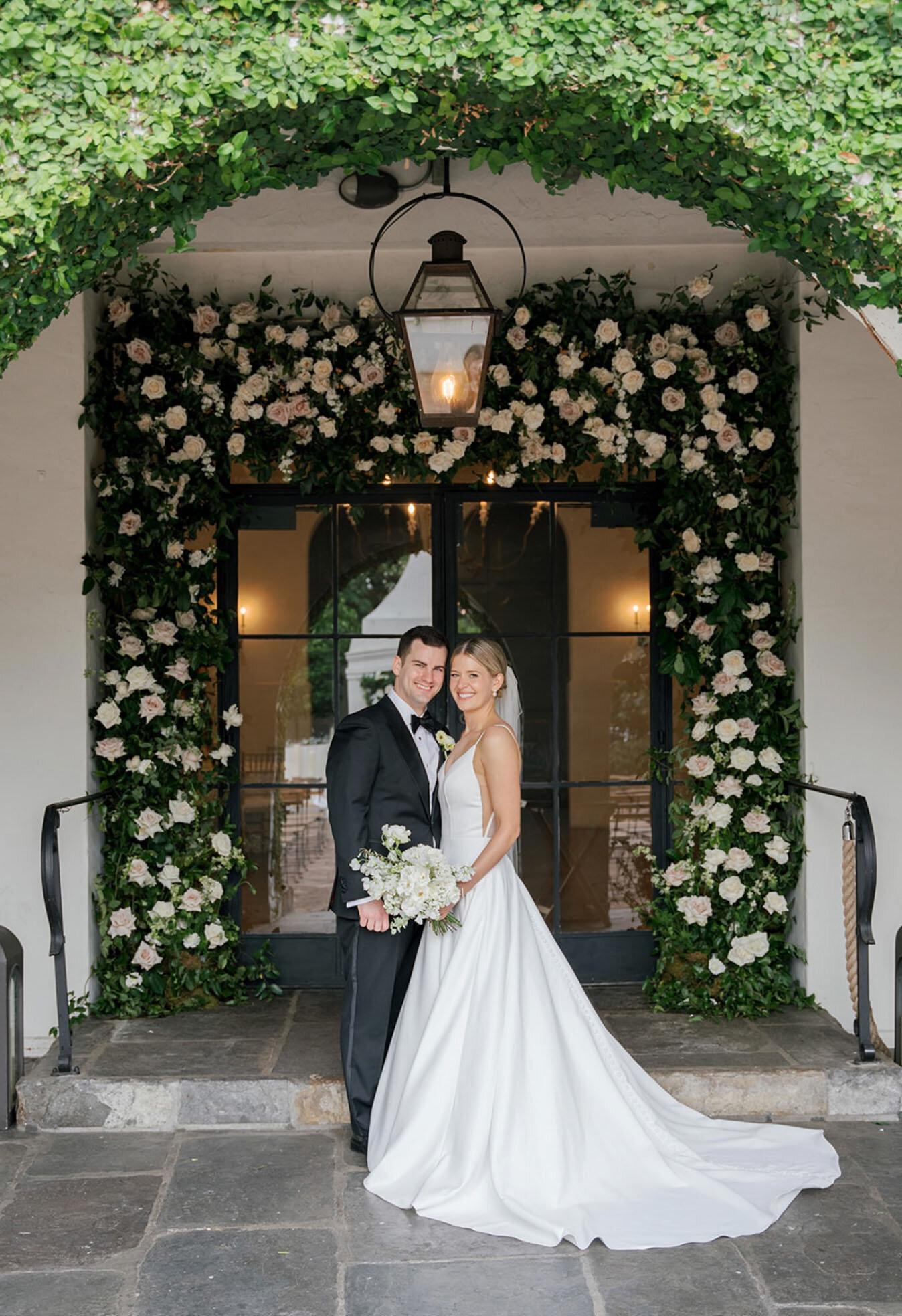 bride and groom standing in front of floral wall