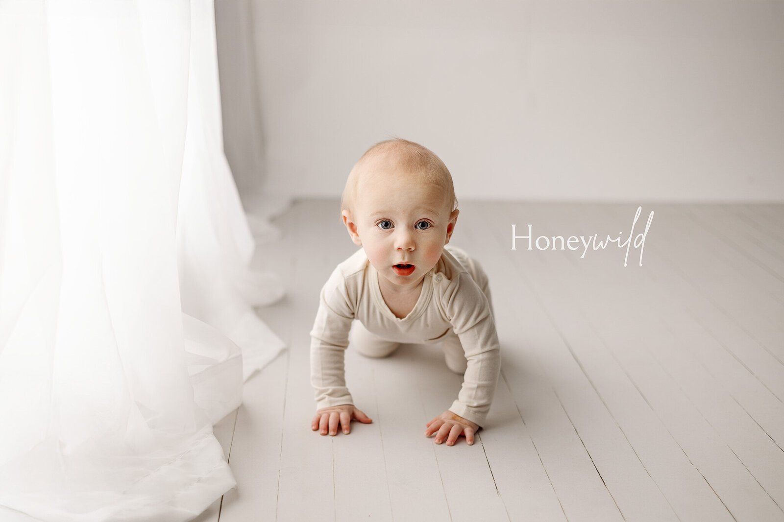 Newborn baby girl peacefully sleeping on a mauve blanket, wearing a delicate lace headband. Captured in a Grand Rapids, MI, studio specializing in luxury newborn photography with soft lighting and timeless details