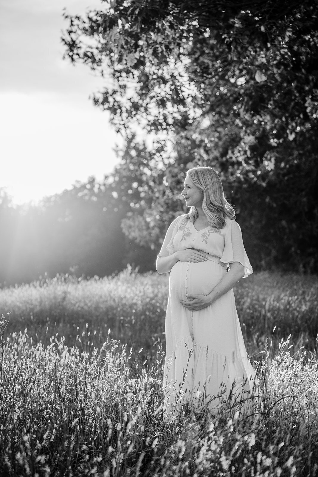 black and white photo of a pregnant woman in a field