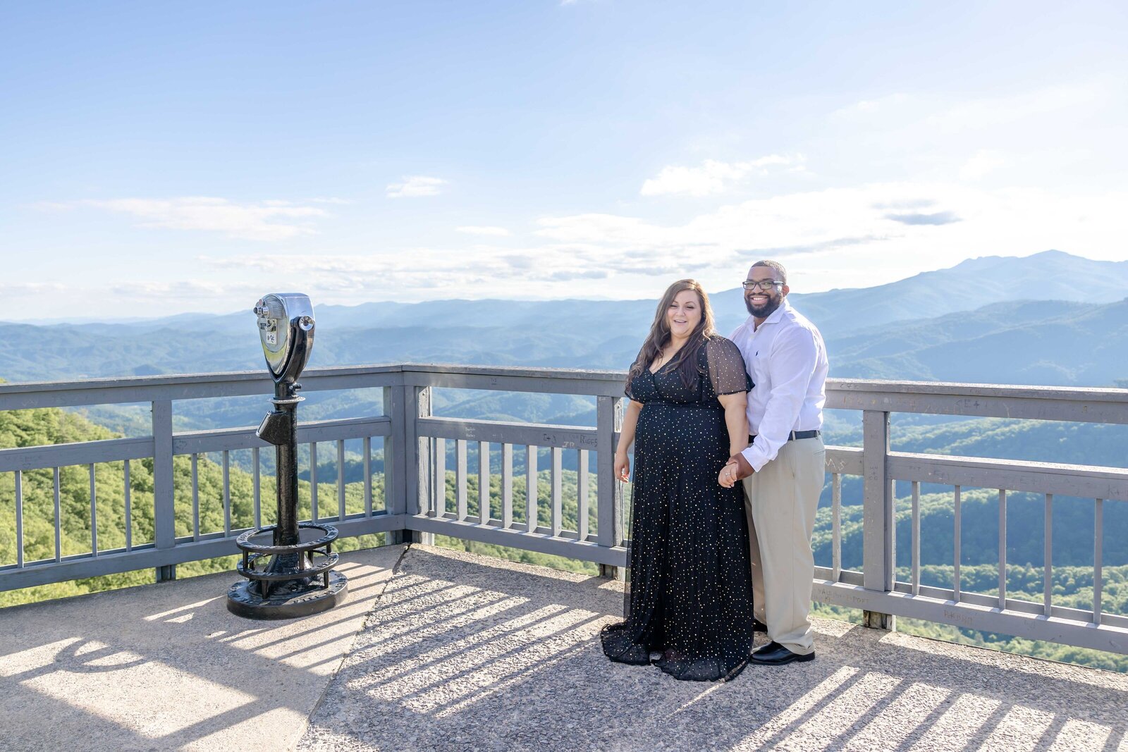 A couple holding hands at a scenic blowing rock mountain overlook in North Carolina, with expansive views in the background. This elegant image captures the essence of destination wedding photography, ideal for couples seeking breathtaking engagement photos in NC.