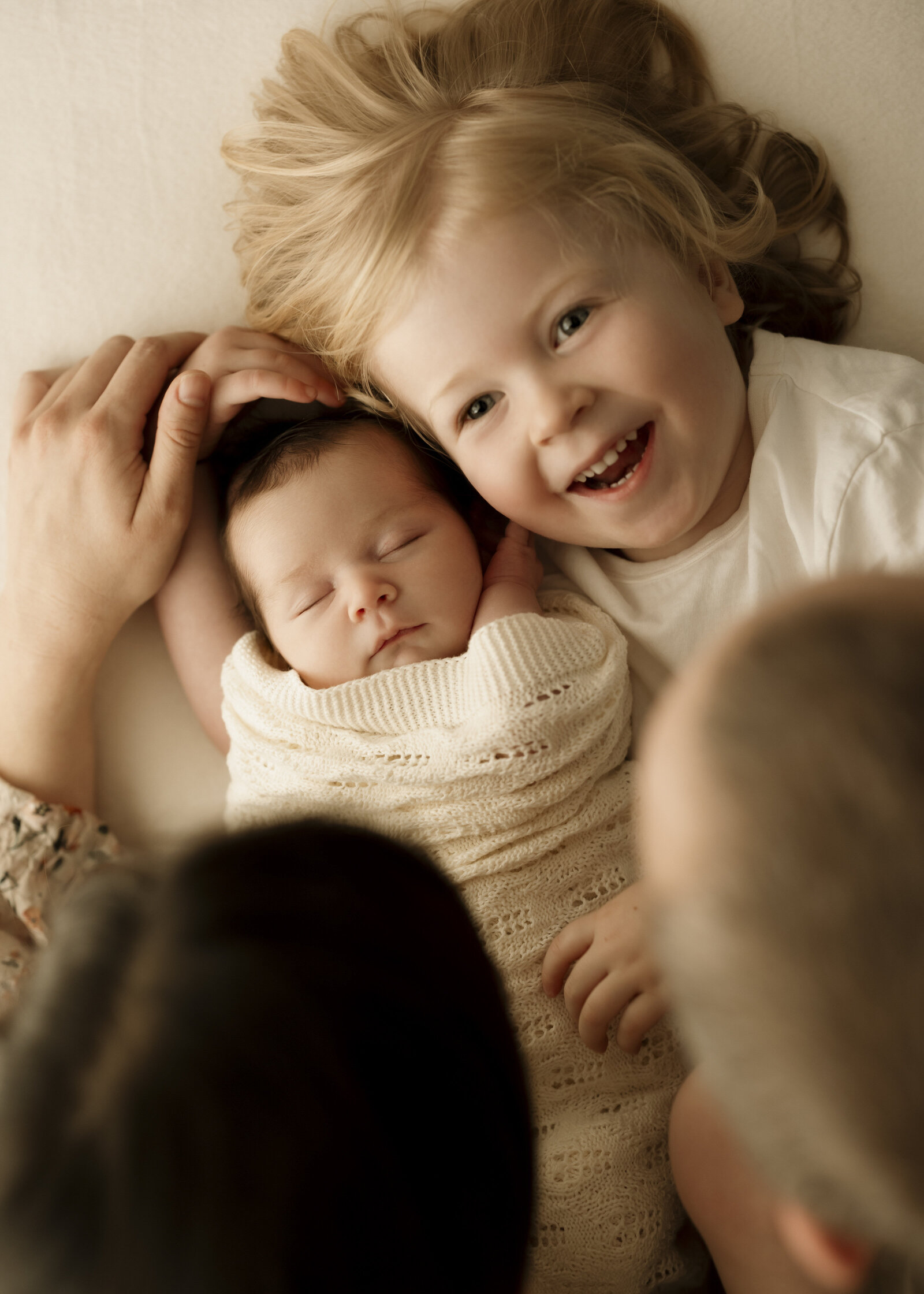 Mum, dad, and baby in a Perth studio newborn photoshoot, capturing the joy of welcoming a new addition to the family.