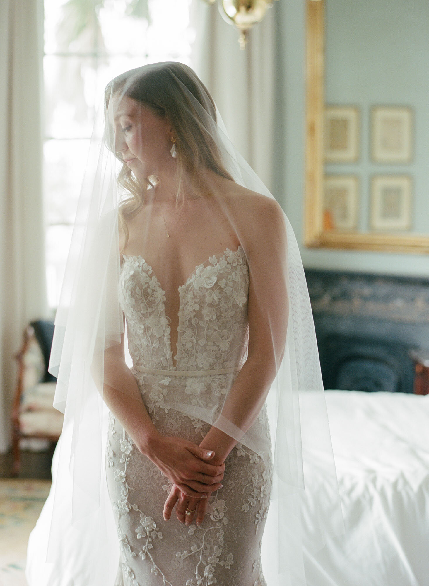 bridal portrait of bride standing underneath veil