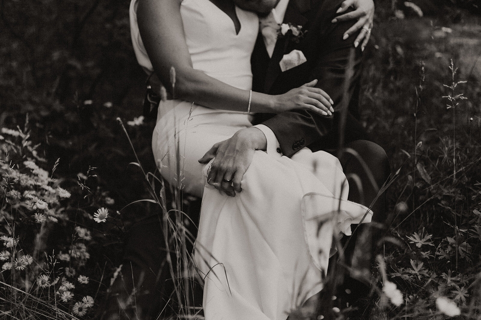 Black and white photo of groom carrying his bride while kissing each other