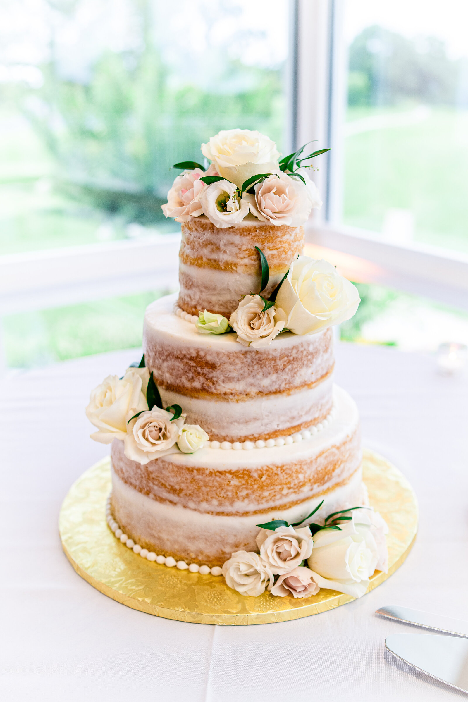 A naked wedding cake decorated with classic off white roses for a wedding in Northern Virginia