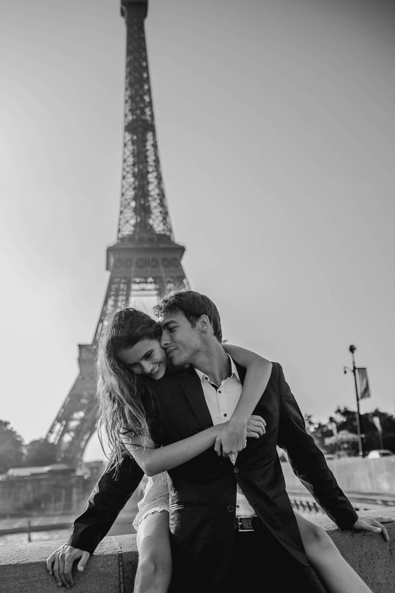 Bride and groom snuggle with the Eiffel Tower behind them, Paris, France