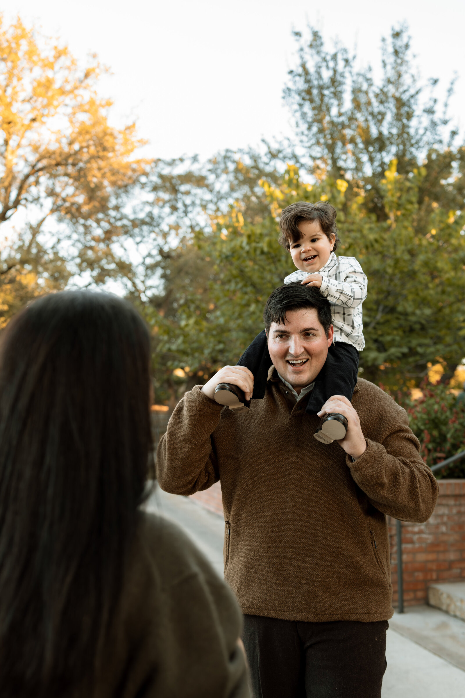 Kid on dad's shoulder looking at mom