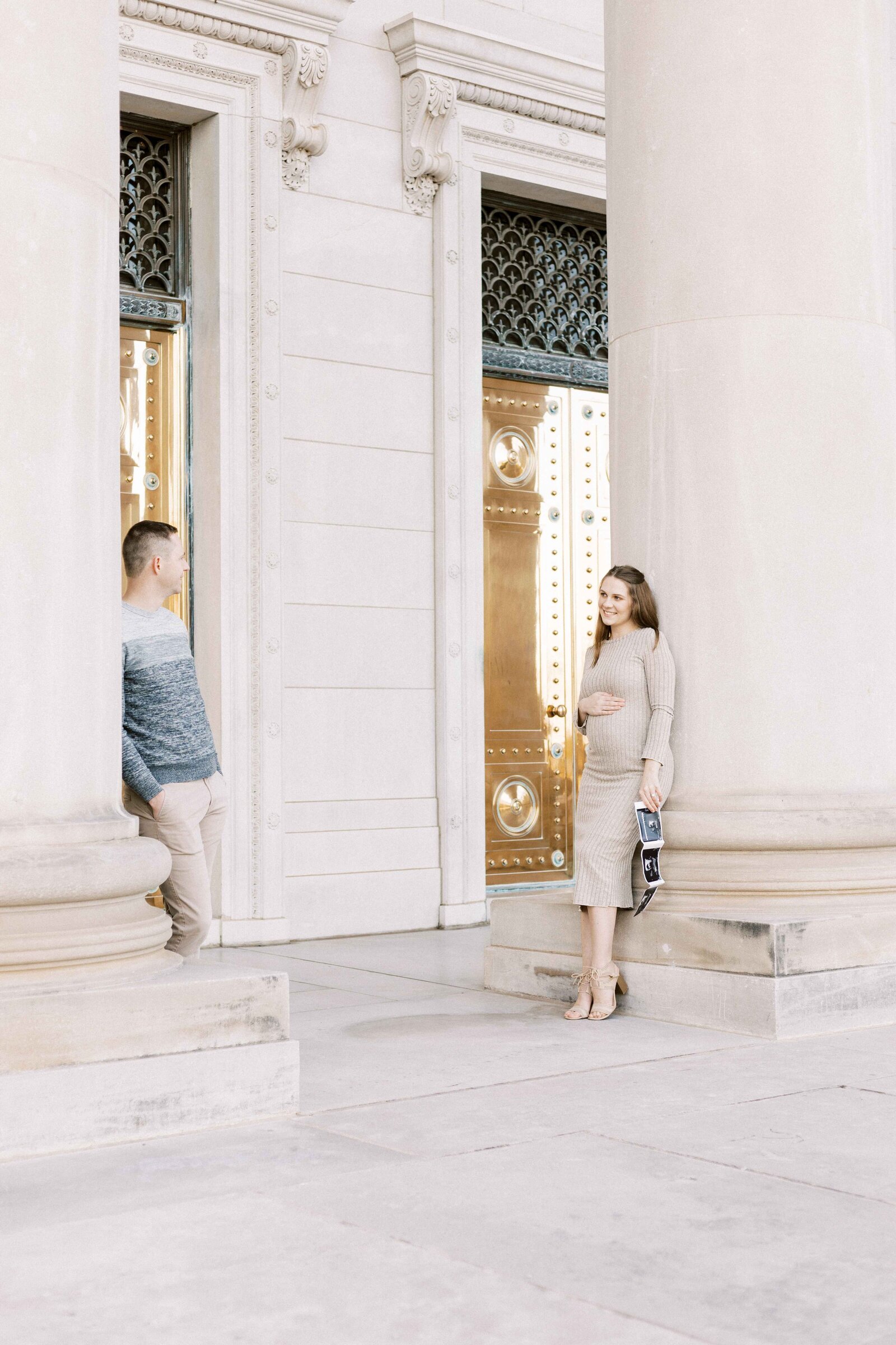 husband and wife holding ultrasound and looking at each other during peoria illinois maternity photos 