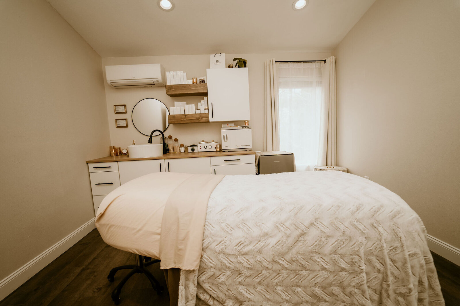 Minimalist, serene spa room at Maven + Grace, featuring curated skincare products and warm lighting.