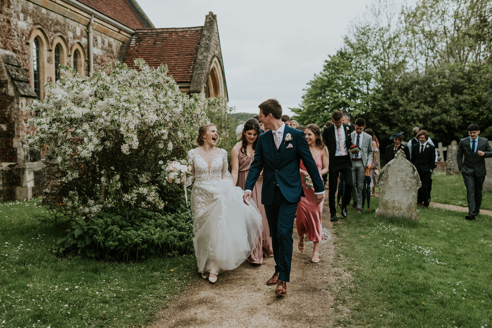 Bride and groom laughing as they walk with their guests