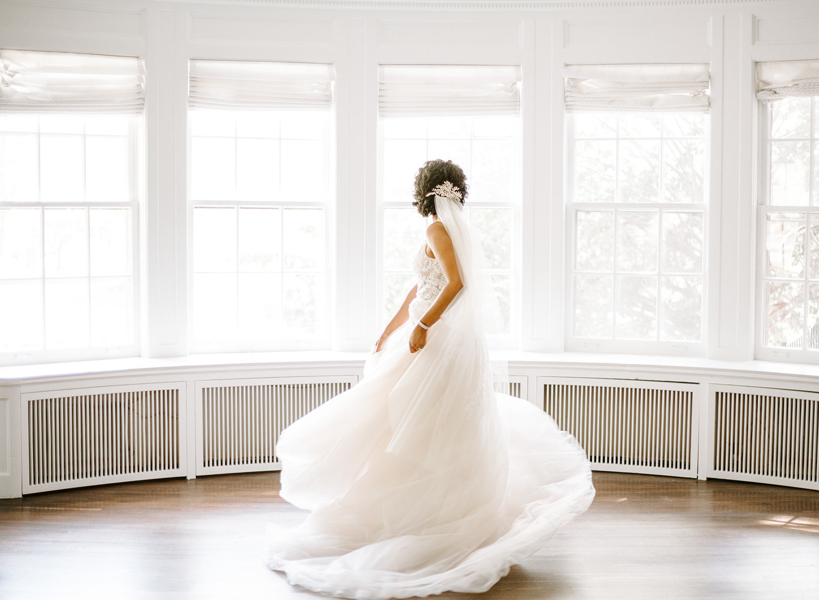 Minneapolis Bride spinning in her wedding dress next to a wall of windows