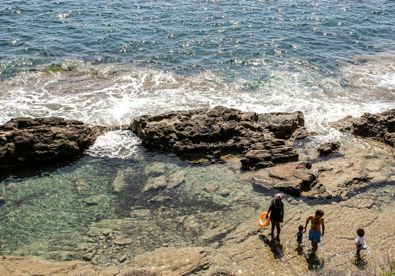 Two people standing on a rocky beach near the ocean