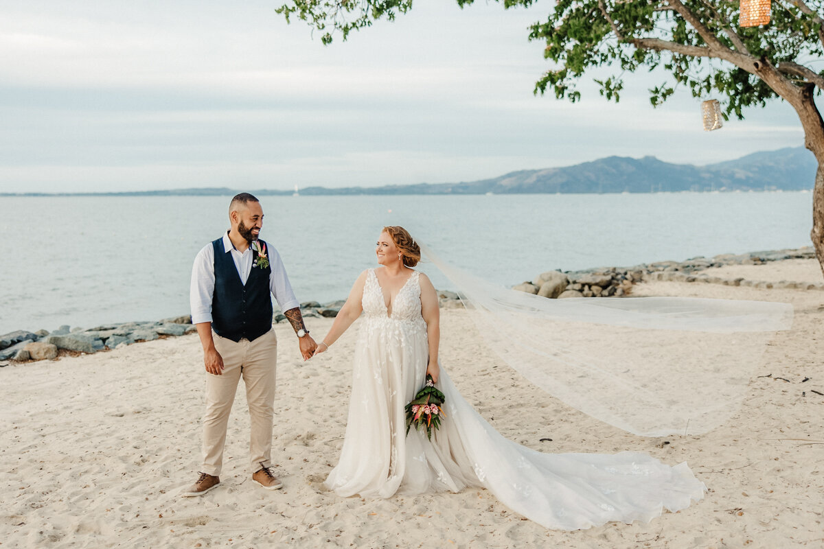 bride and groom holding hands on the beach