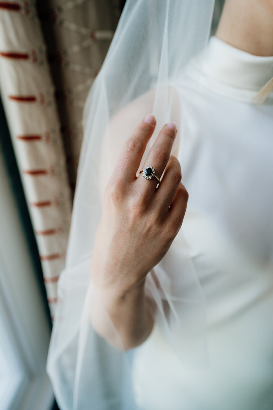 editorial wedding photo of a bride's hand holding a veil with an engagement ring on taken in london