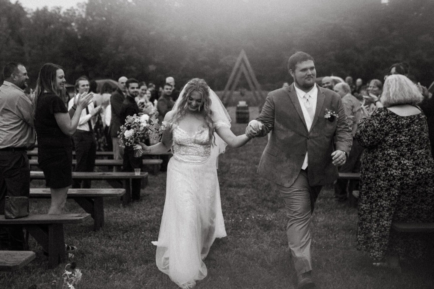 Bride and groom walking hand-in-hand down the aisle with guests celebrating