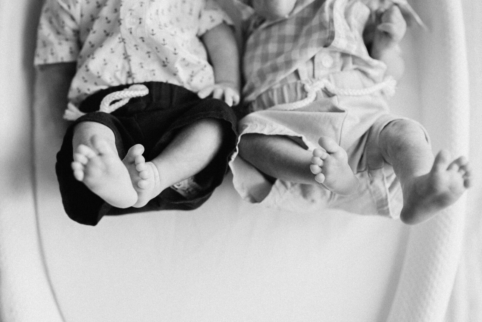 A black and white photo of twin baby feet sticking up in the air together