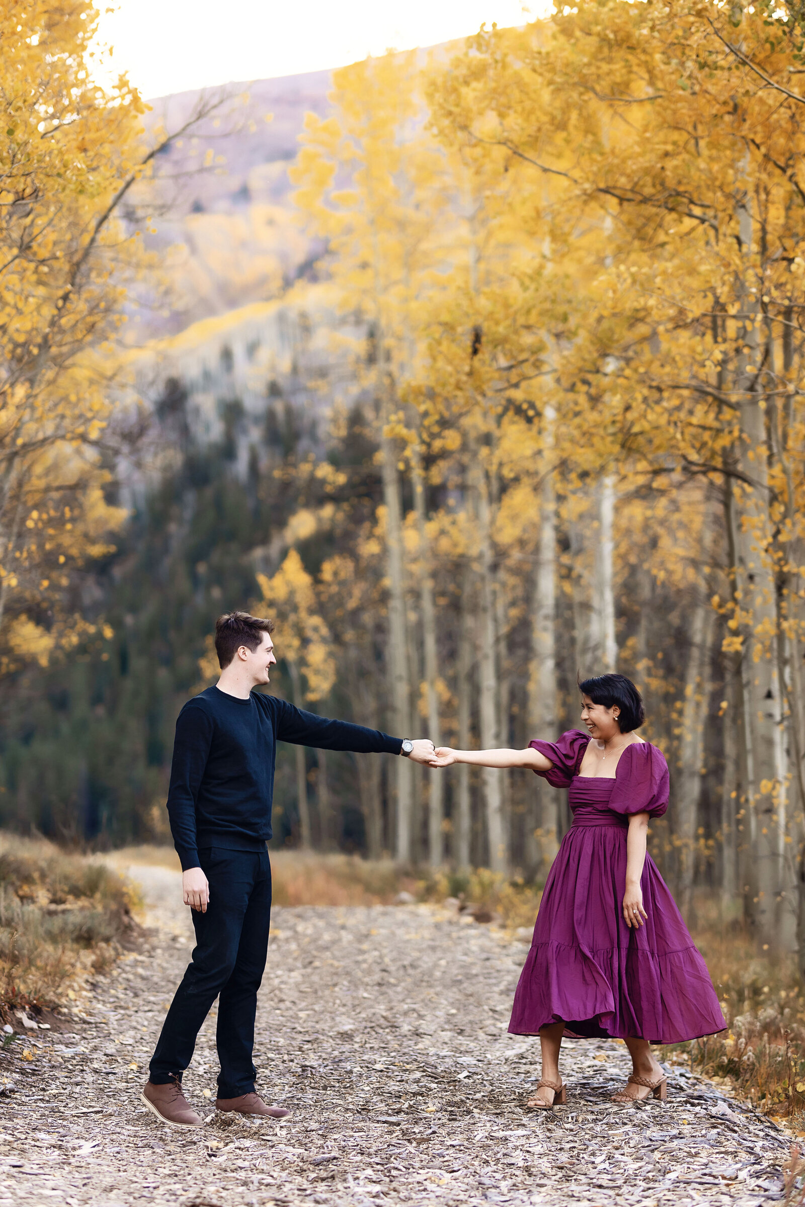A man and woman dance in the beautiful fall  foliage in Aspen, Colorado for their engagement photoshoot.