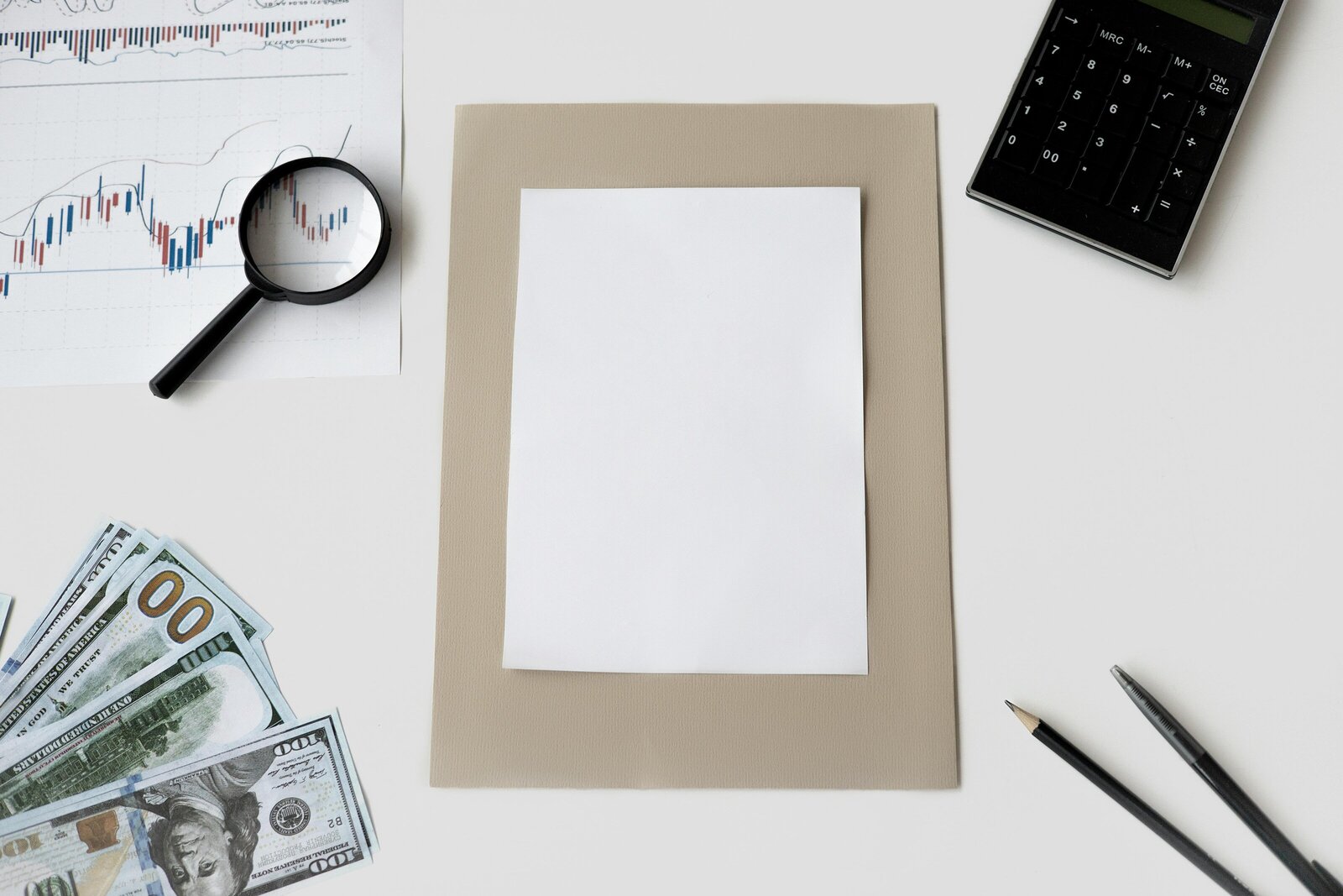 Picture of desk layout with items such as a magnifying glass, piece of paper, money, a chart, part of a calculator.