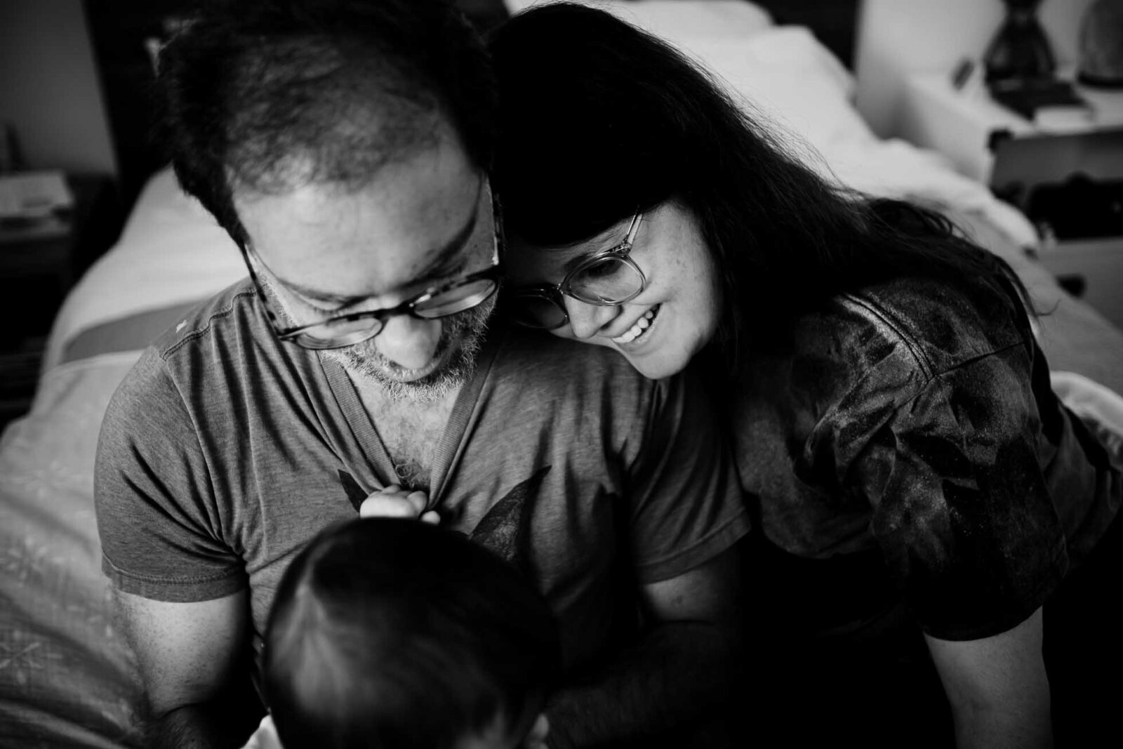 black & white image of couple gazing lovingly at their baby