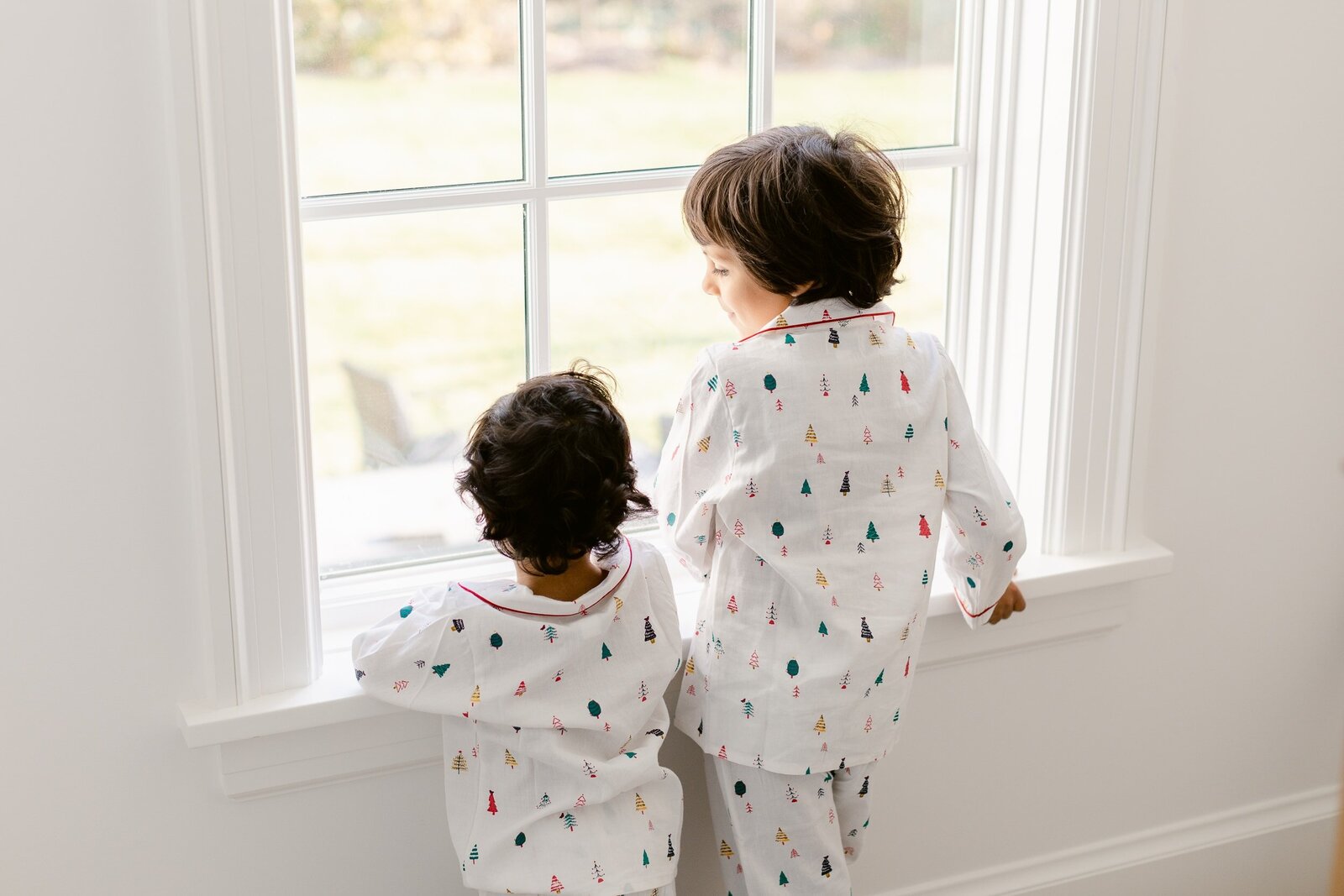 brothers in christmas pajamas at the window