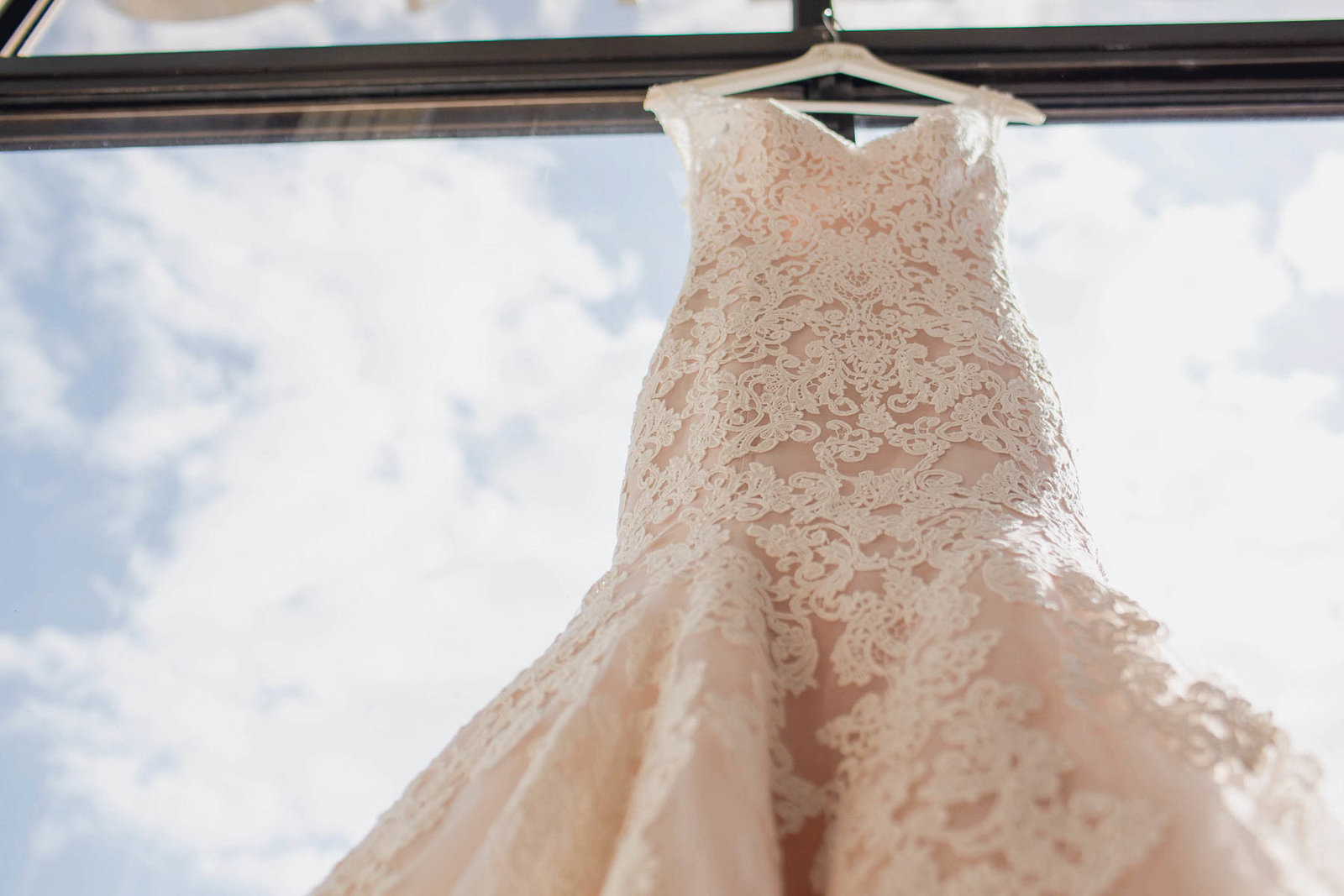Dress hangs in window overlooking the water and boatyard, Destination wedding, Hyatt Regency, Sarasota, Florida. Kate Timbers Photography.