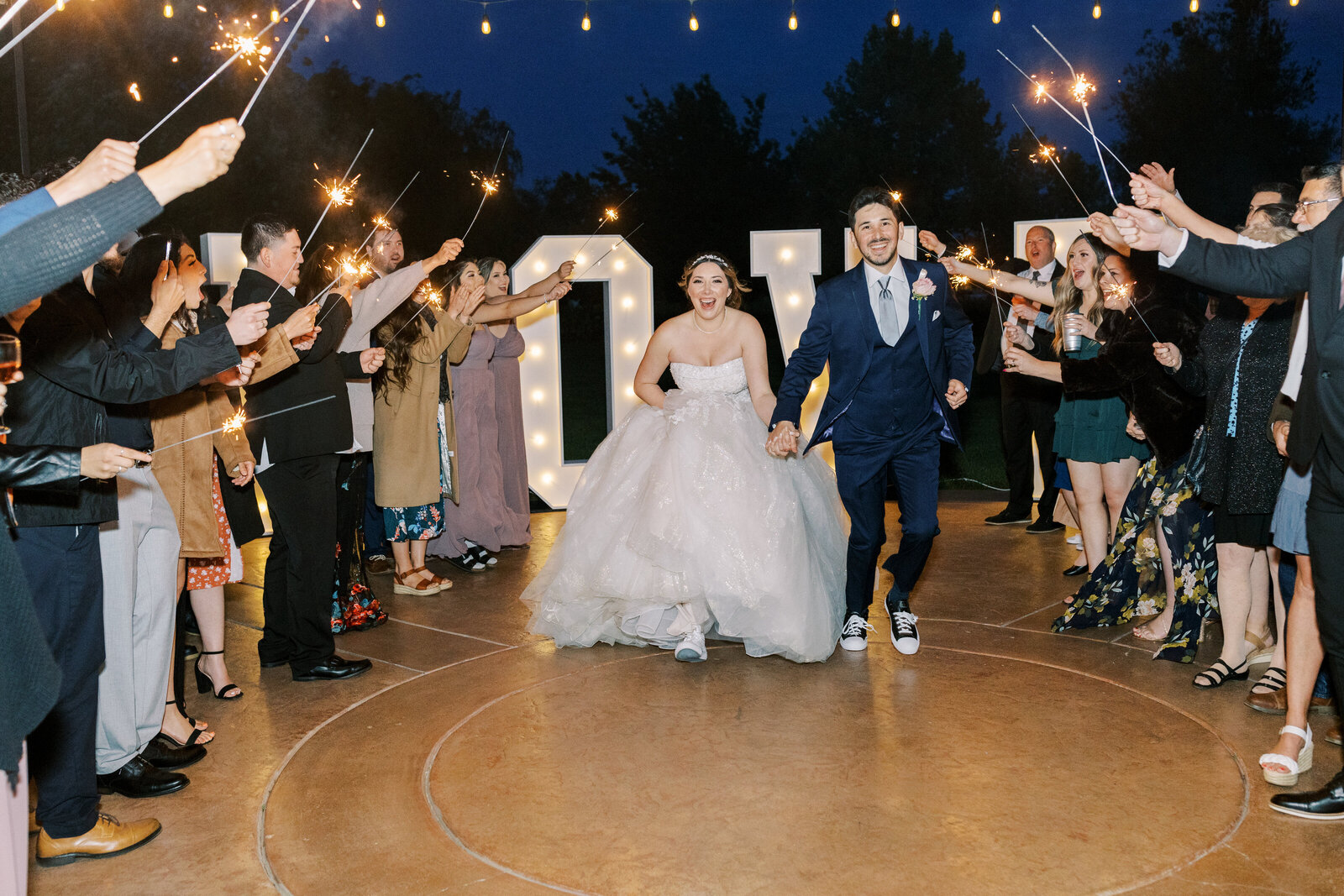 grand exit for california wedding with bride and groom holding hands and running around their guests who are holding sparklers captured by sacramento wedding photographer