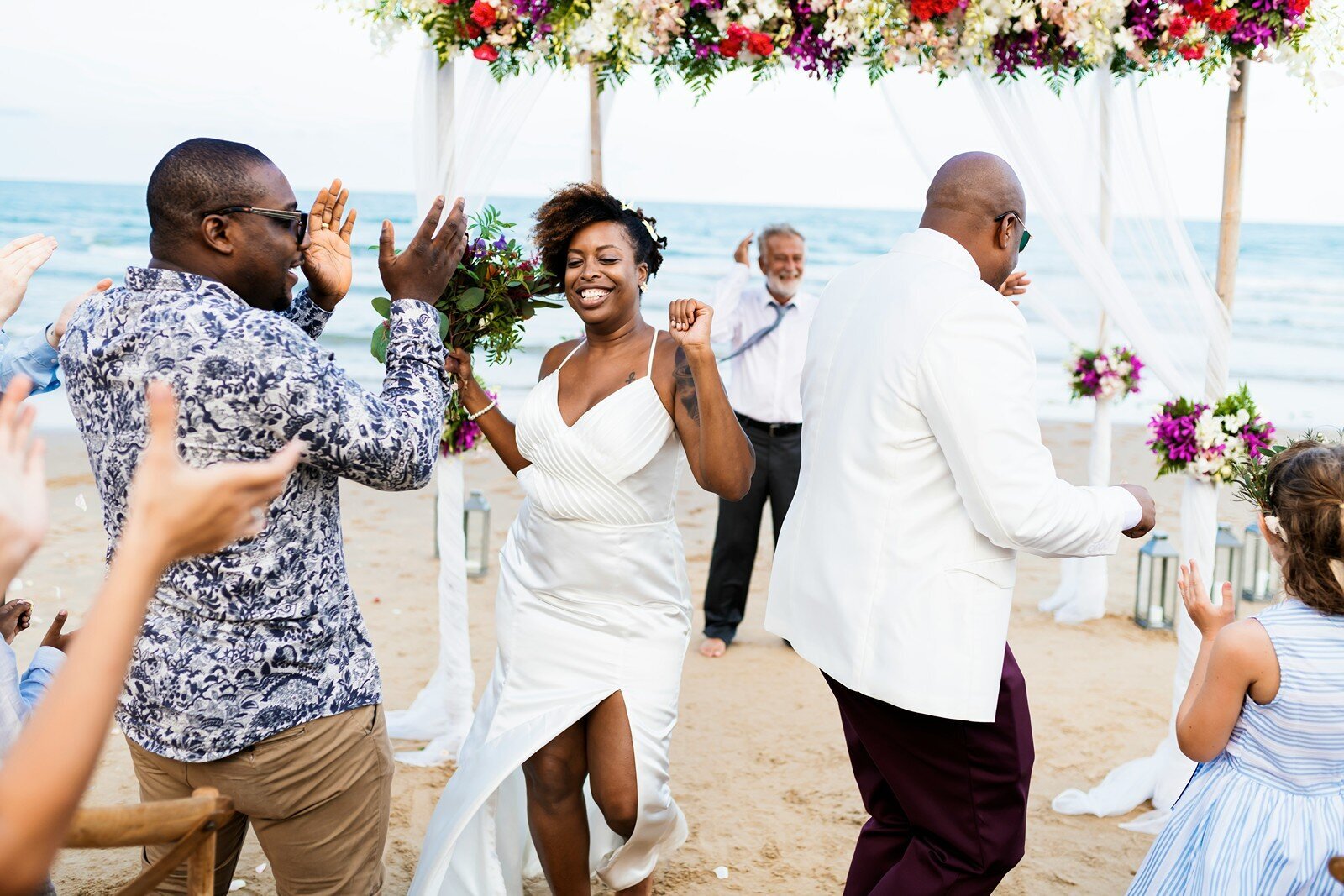 Bride dancing joyfully at a beach wedding ceremony