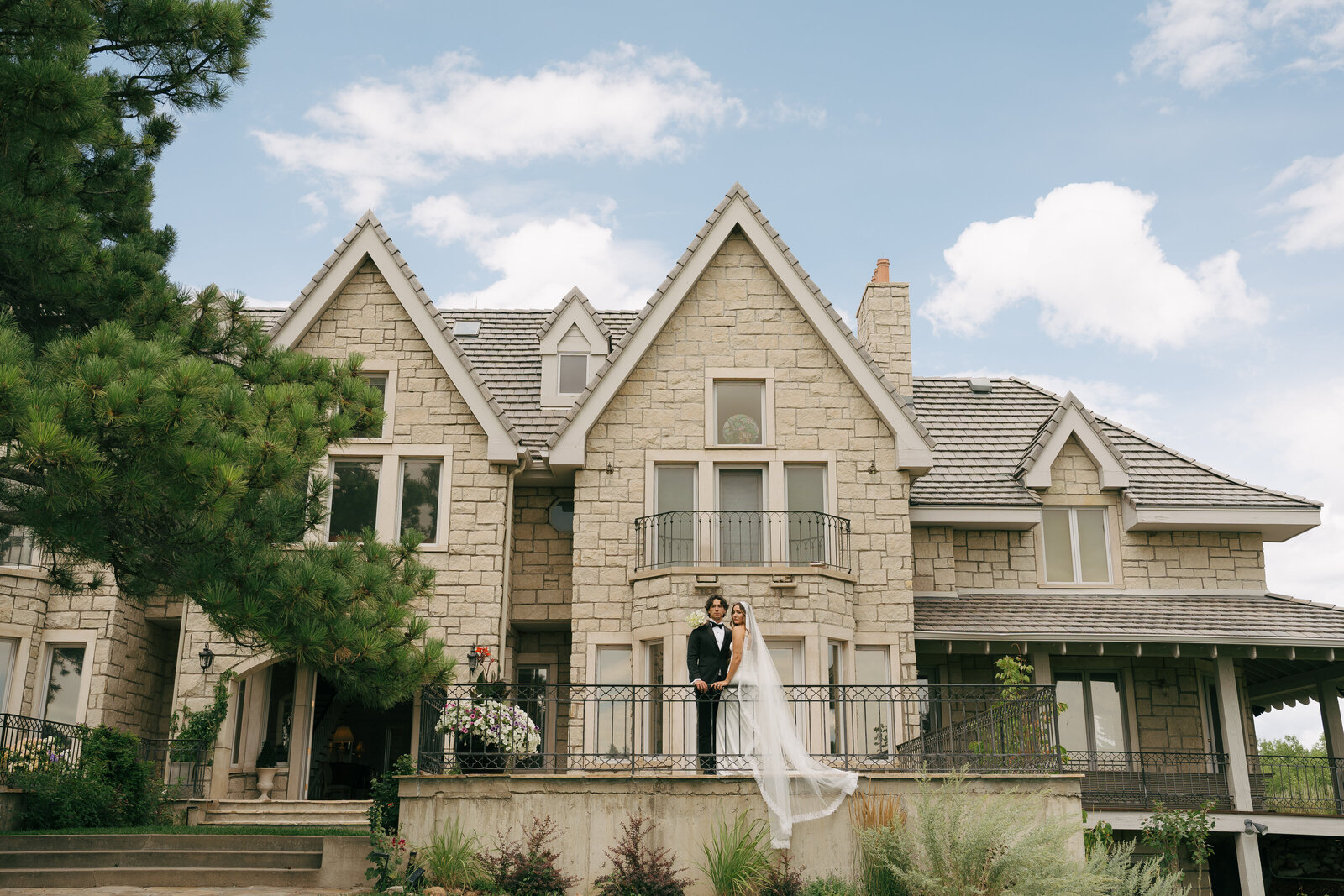 A bride and a groom standing along a railing outside of their wedding venue in Boulder, Colorado. 