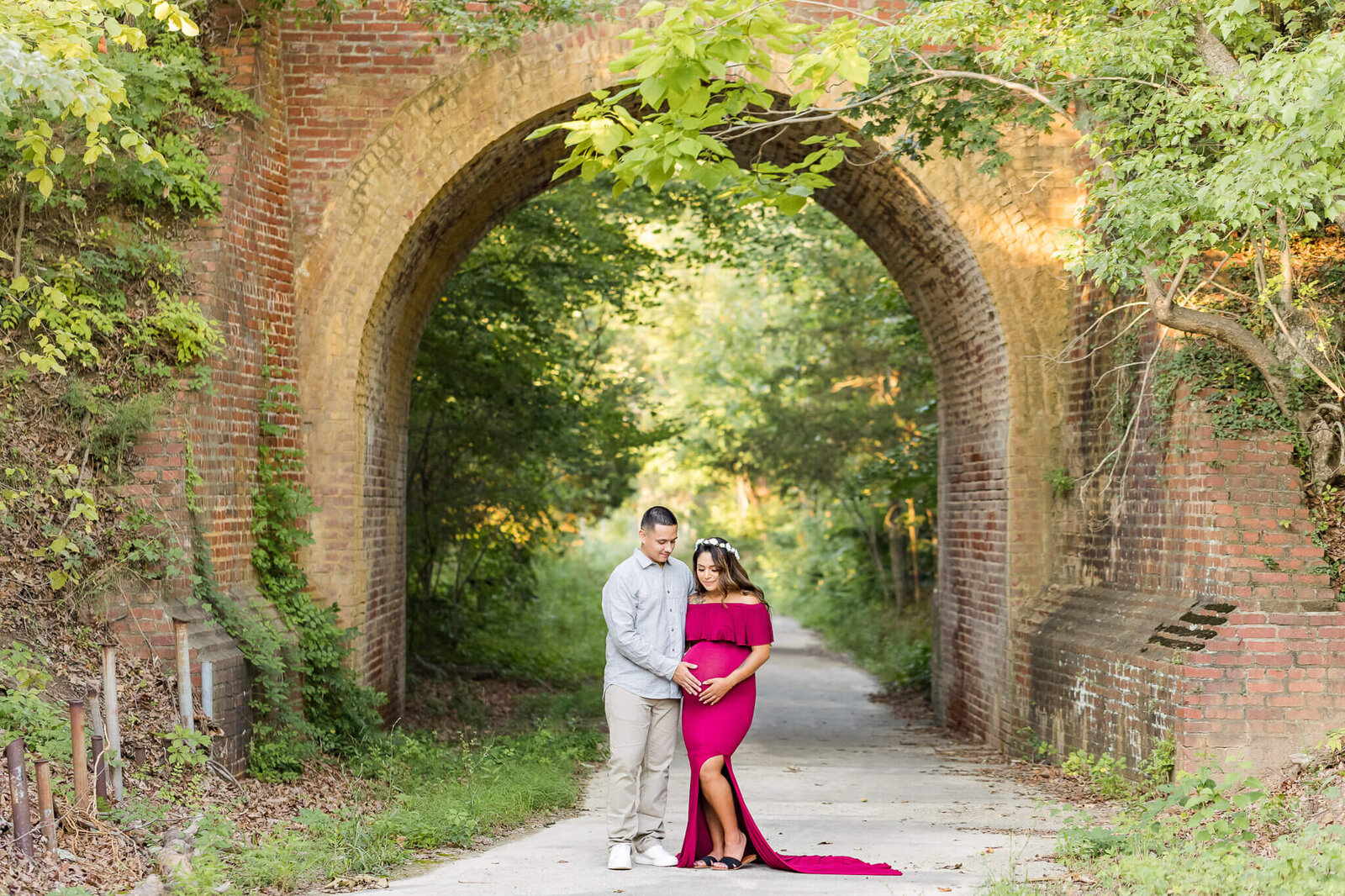 A pregnant couple standing under a bridge in Lorton, Virginia.