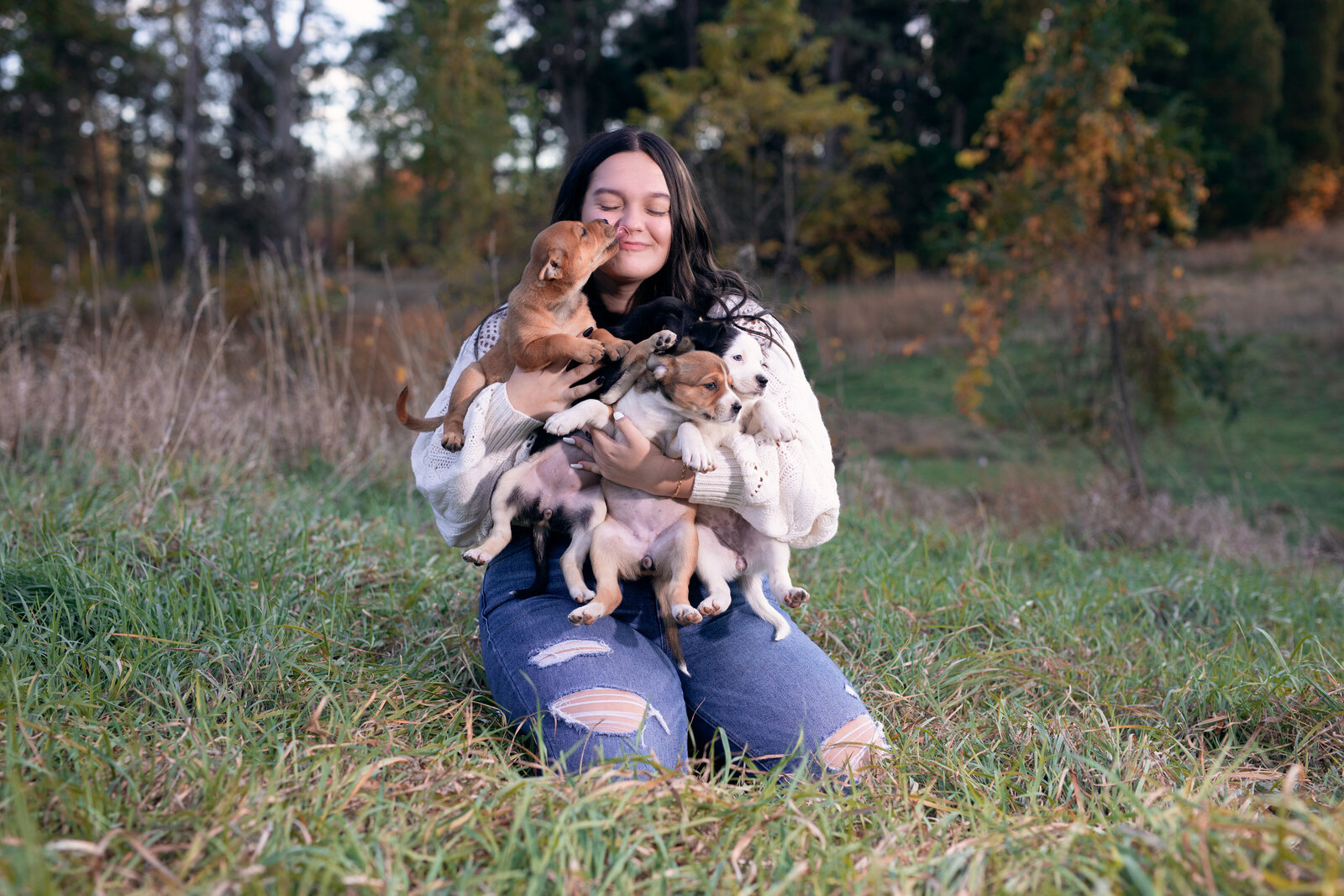 Senior holds a handful of puppies during a senior photo shoot at Pioneers Park