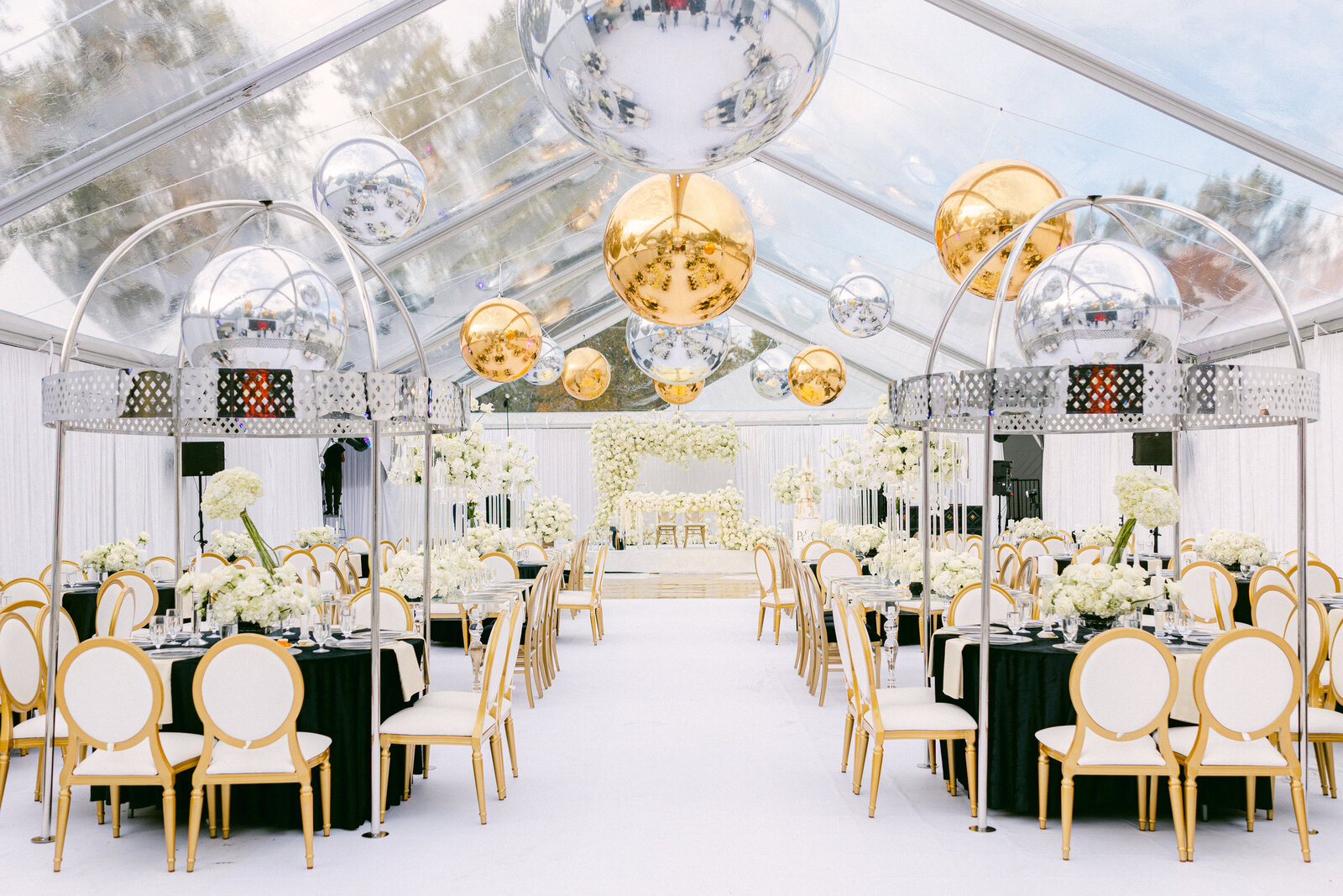 wide shot of a white wedding venue with black tables and white chairs