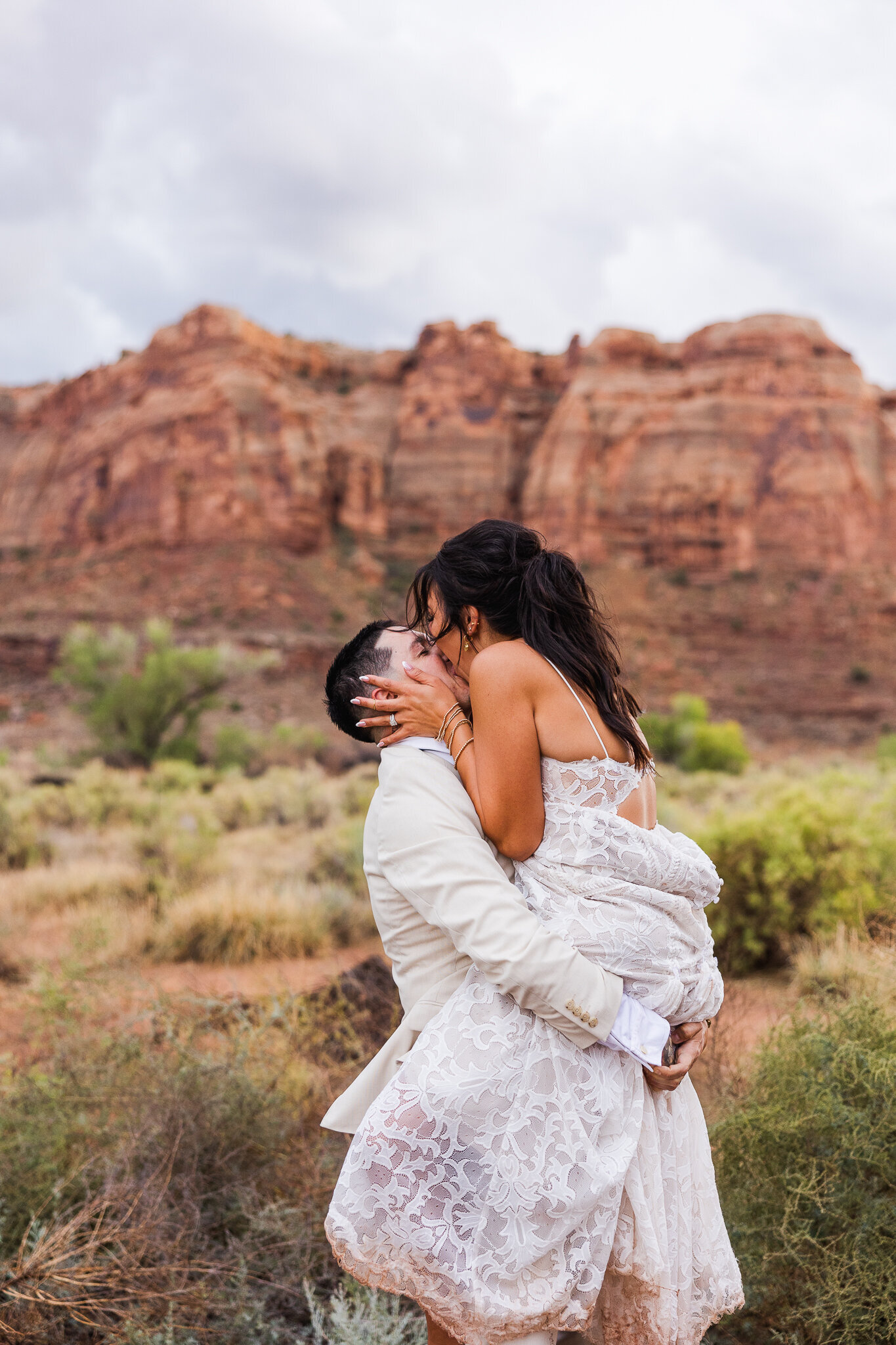 Groom picking up bride and kissing during photos at the Red Earth Venue