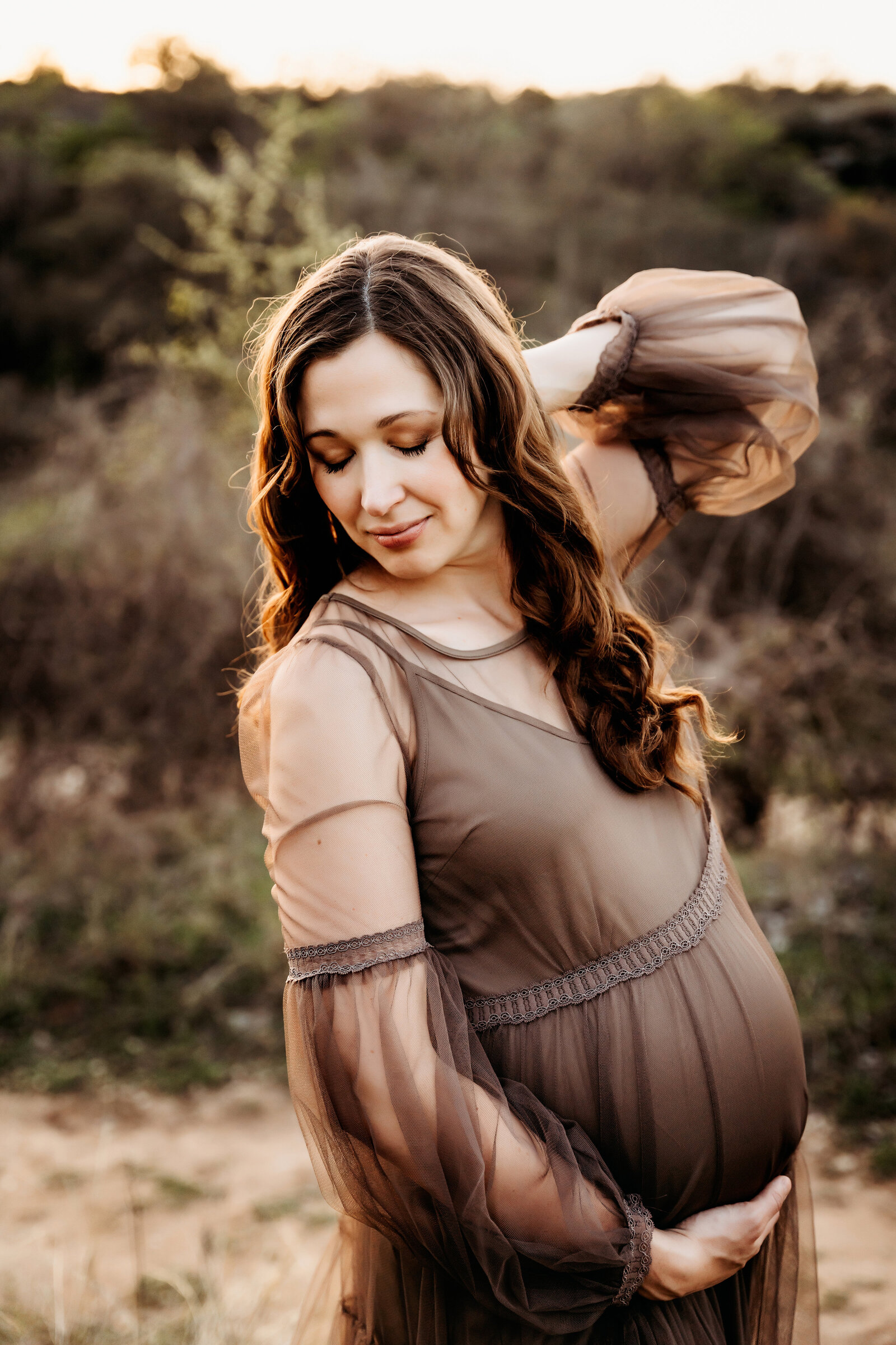 Maternity Photographer, an expectant mother wears a dress in the outdoors