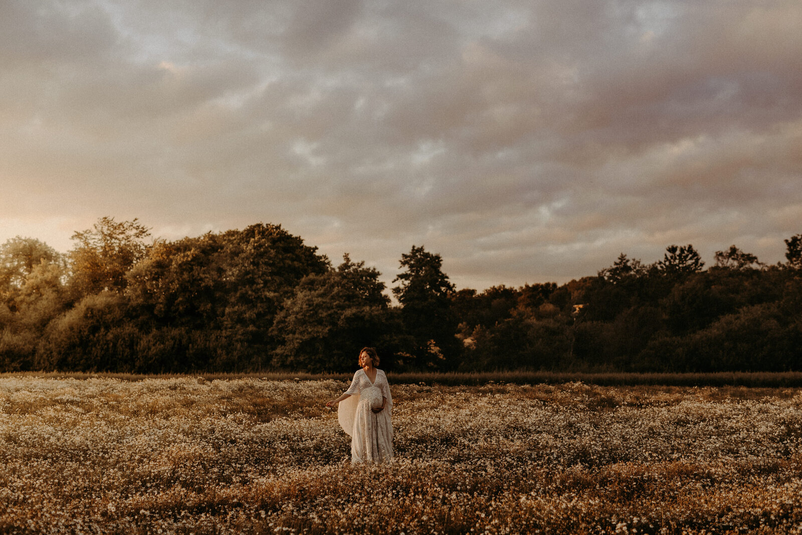 en gravidfotografering på ett blomfält där mamman är iklädd en bohemisk gravidklänning
