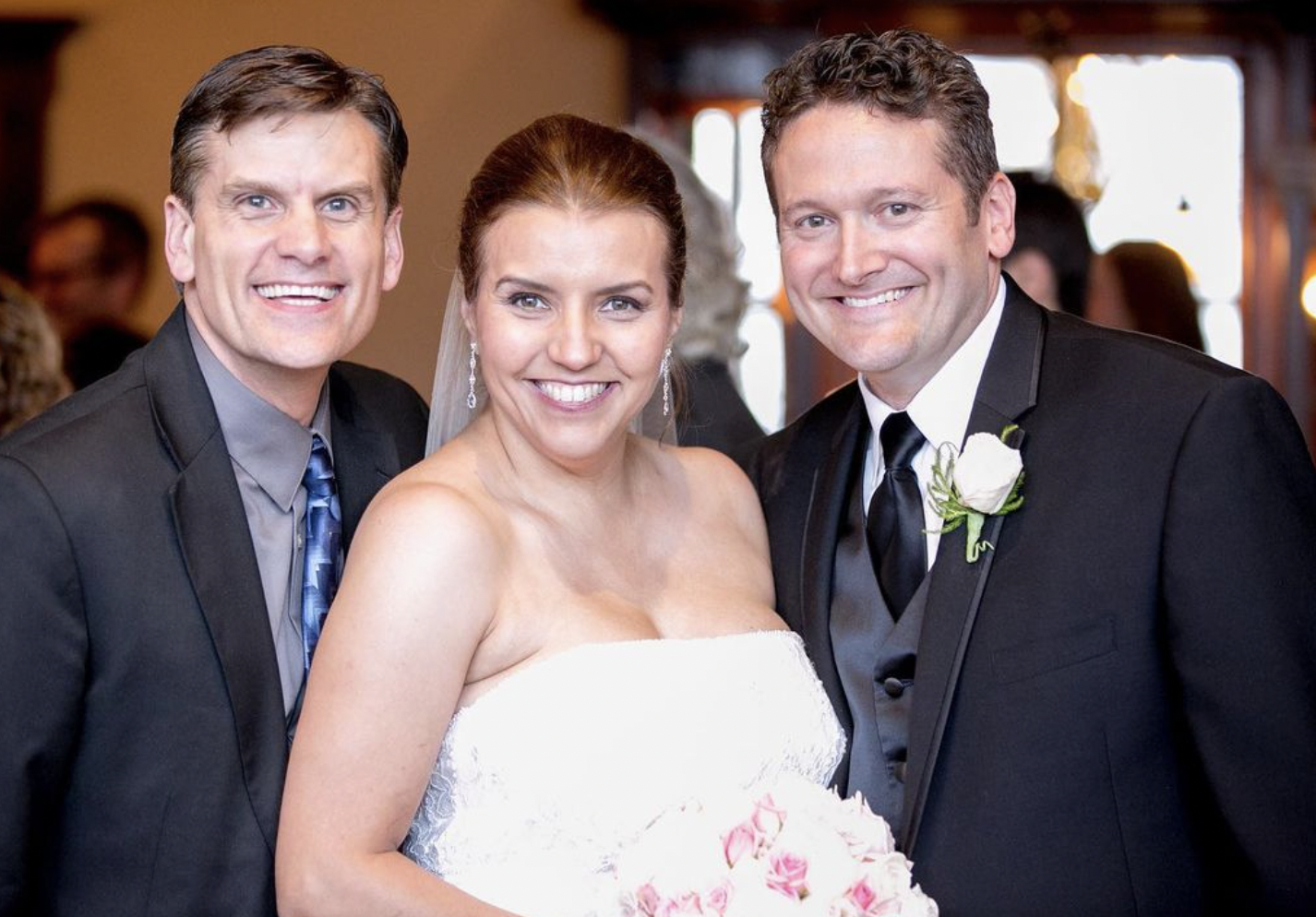 Bride, groom, and officiant smile for portrait