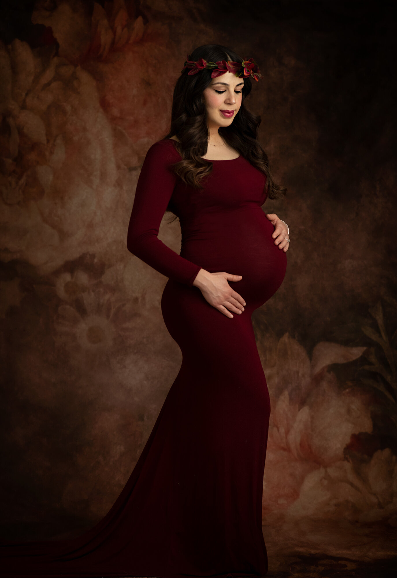 Pregnant woman in full length red fitted dress with floral halo