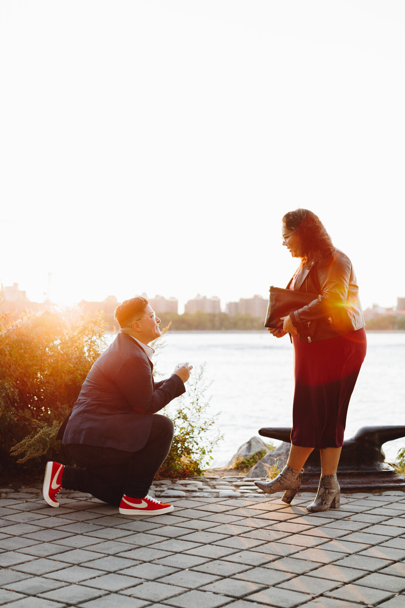 Man on one knee presenting a ring by the Hudson River with the couple's dog beside them, captured by Hudson Valley proposal photographers