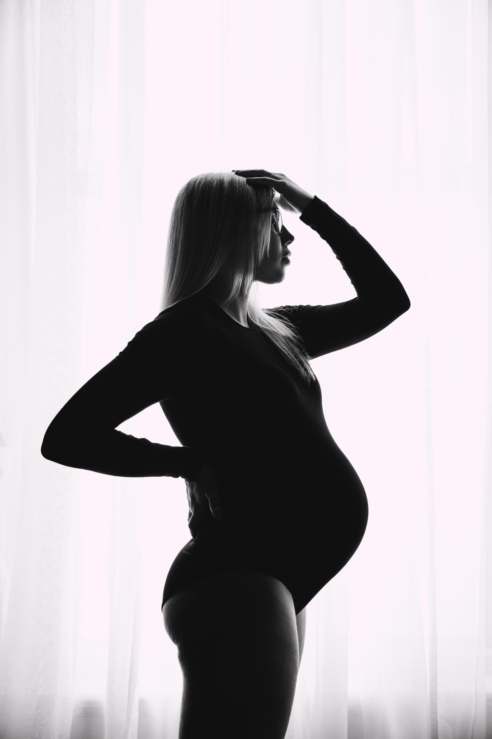 Pregnant woman embracing her belly during a boudoir session in Kansas City