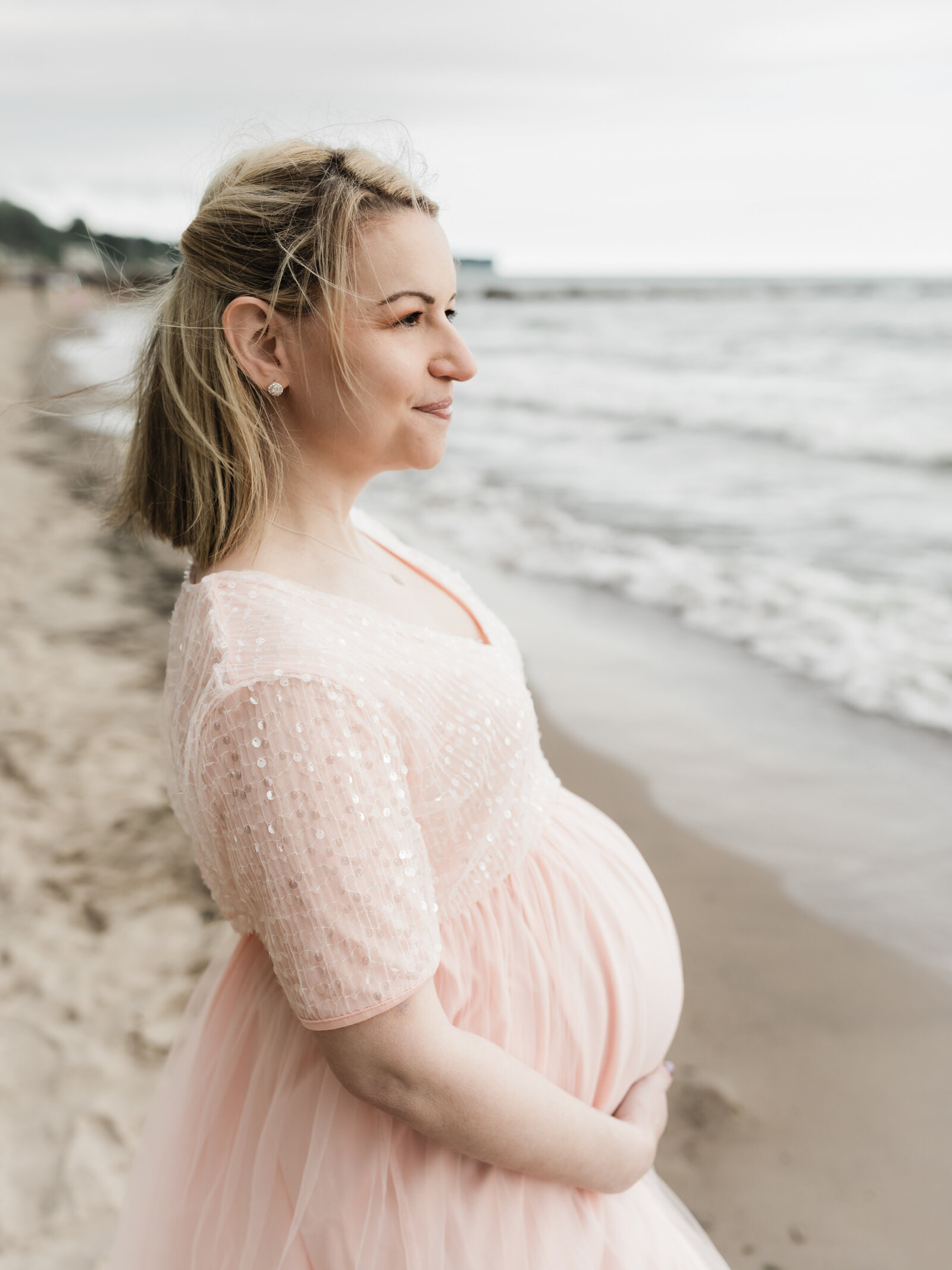 pregnant mother in pink maternity gown for photoshoot on the beach