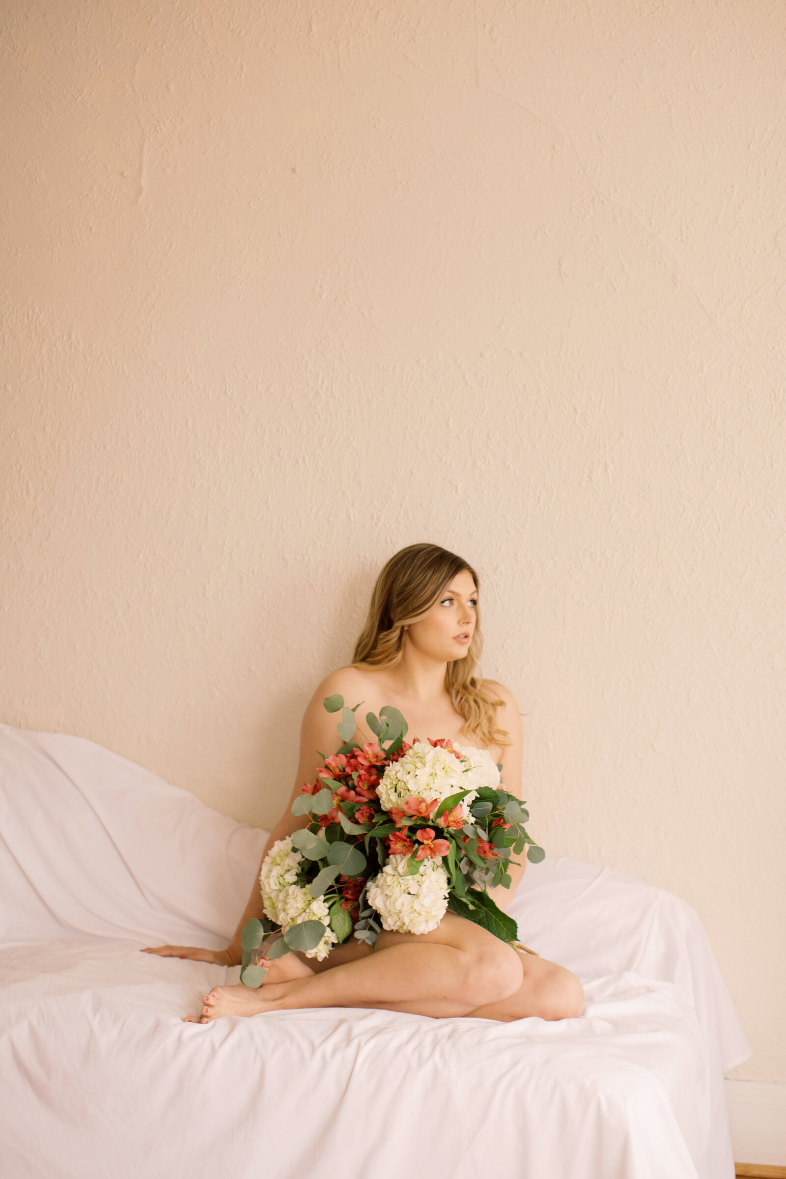 Woman sitting on a bed holding bouquet of flowers