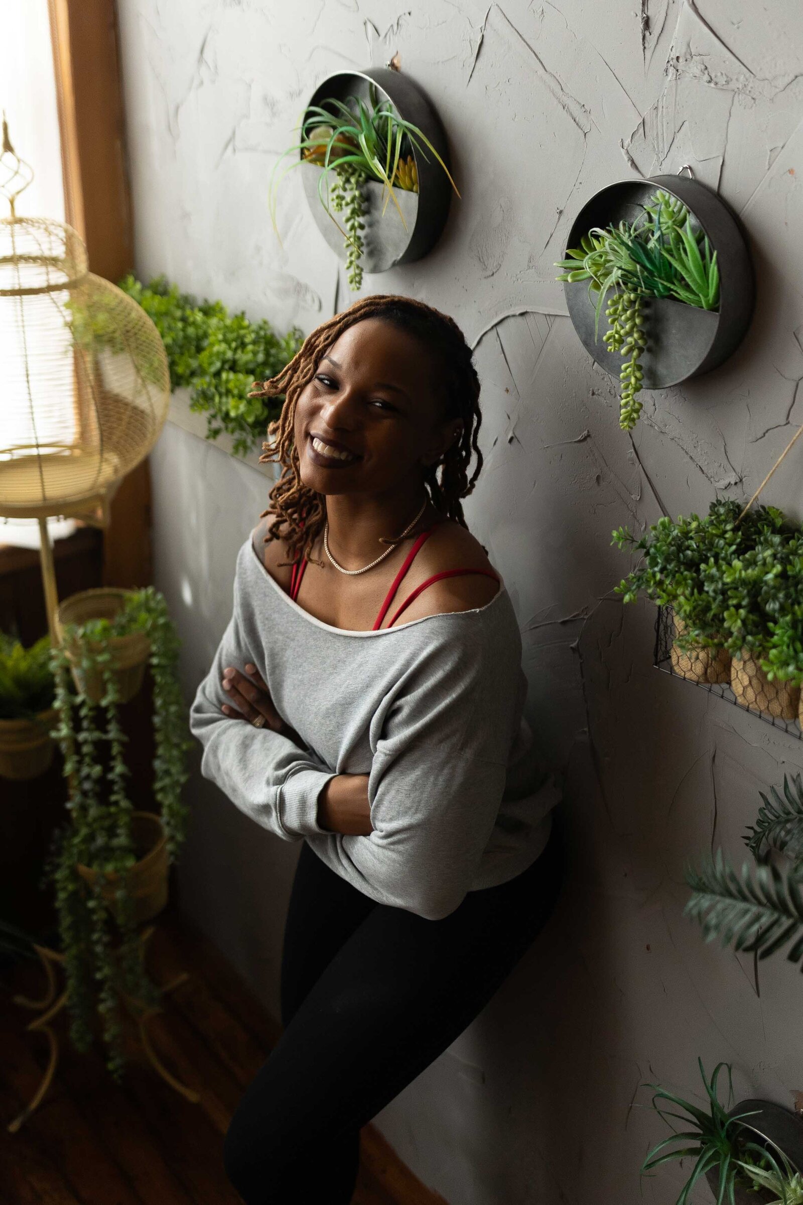 woman leaning on a wall with green plants around it