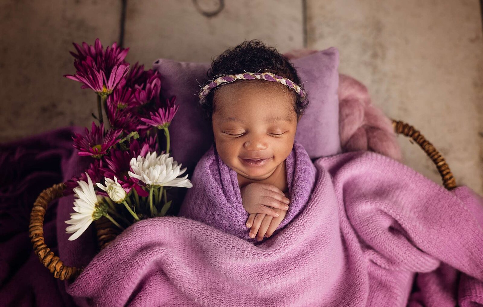 A newborn girl wrapped in soft purple and pink blankets, captured by Bia Schaefer, Orlando's in-home newborn photographer.
