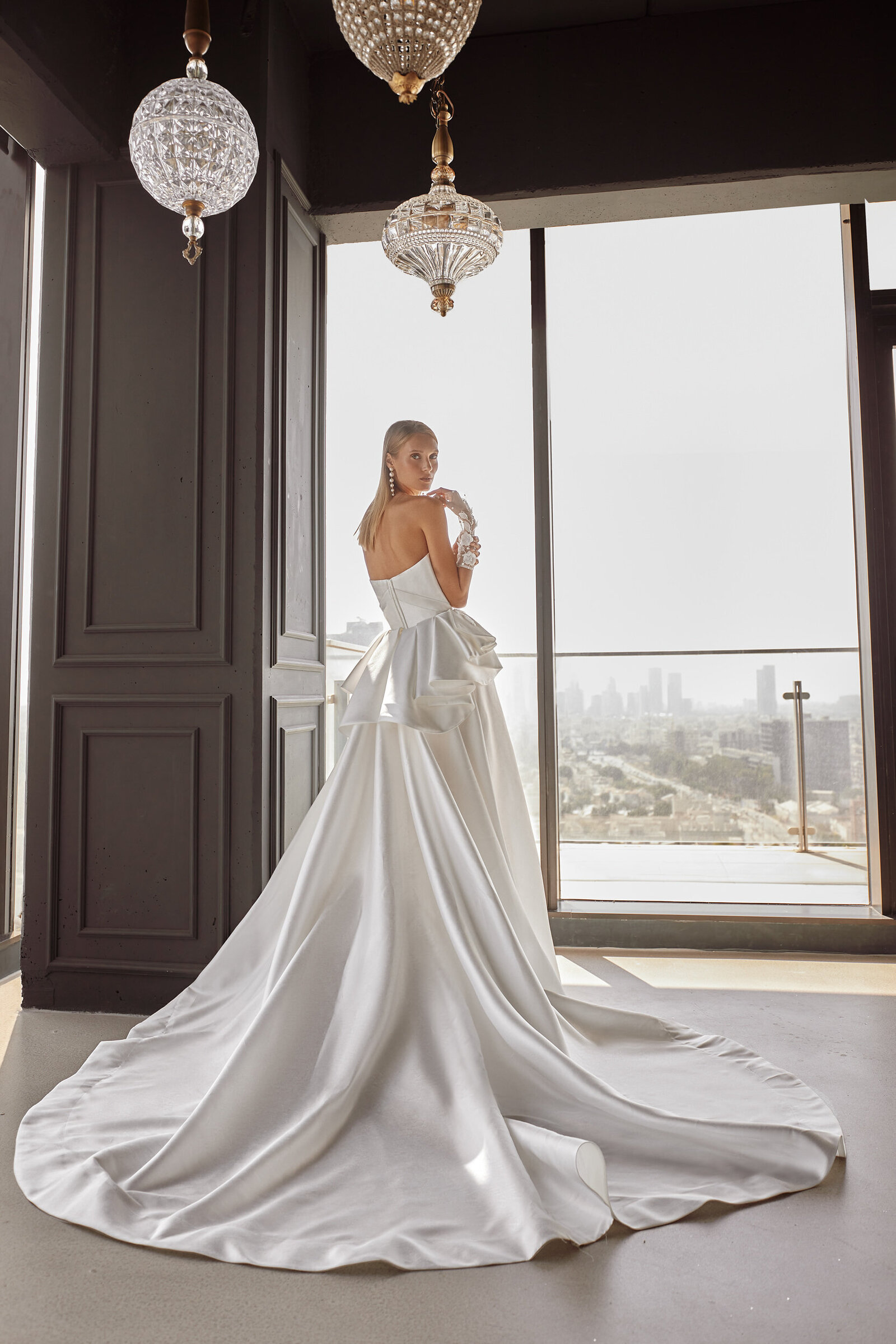 bride wearing white satin wedding dress with long train and bow