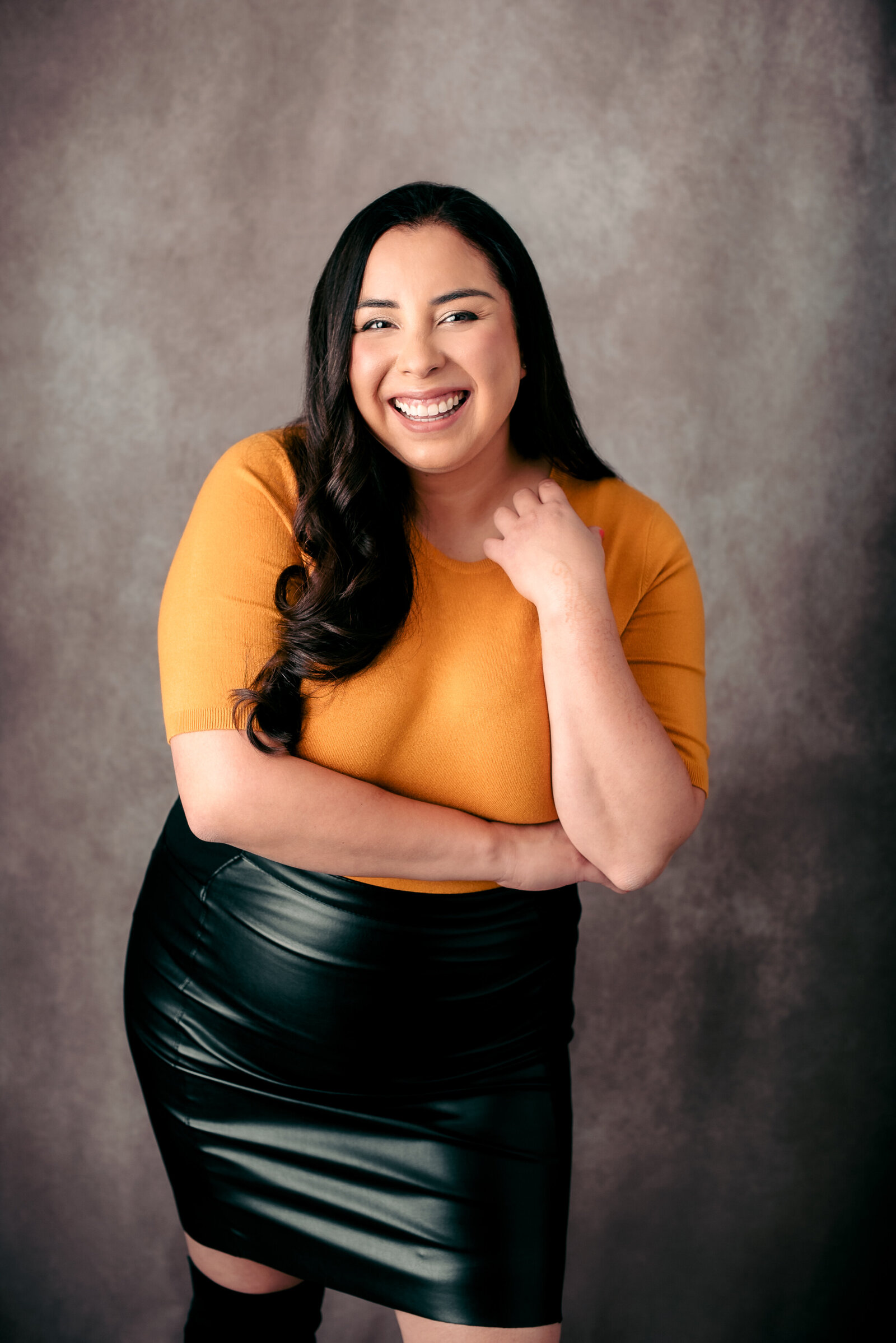 Headshot of a real estate agent wearing an orange sweater and leather skirt