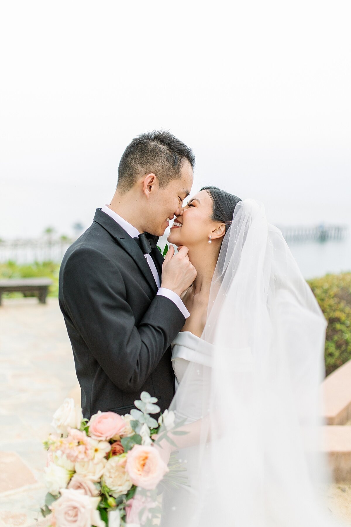 Bride and groom kissing overlooking San Clemente Pier at Casa Romantica.