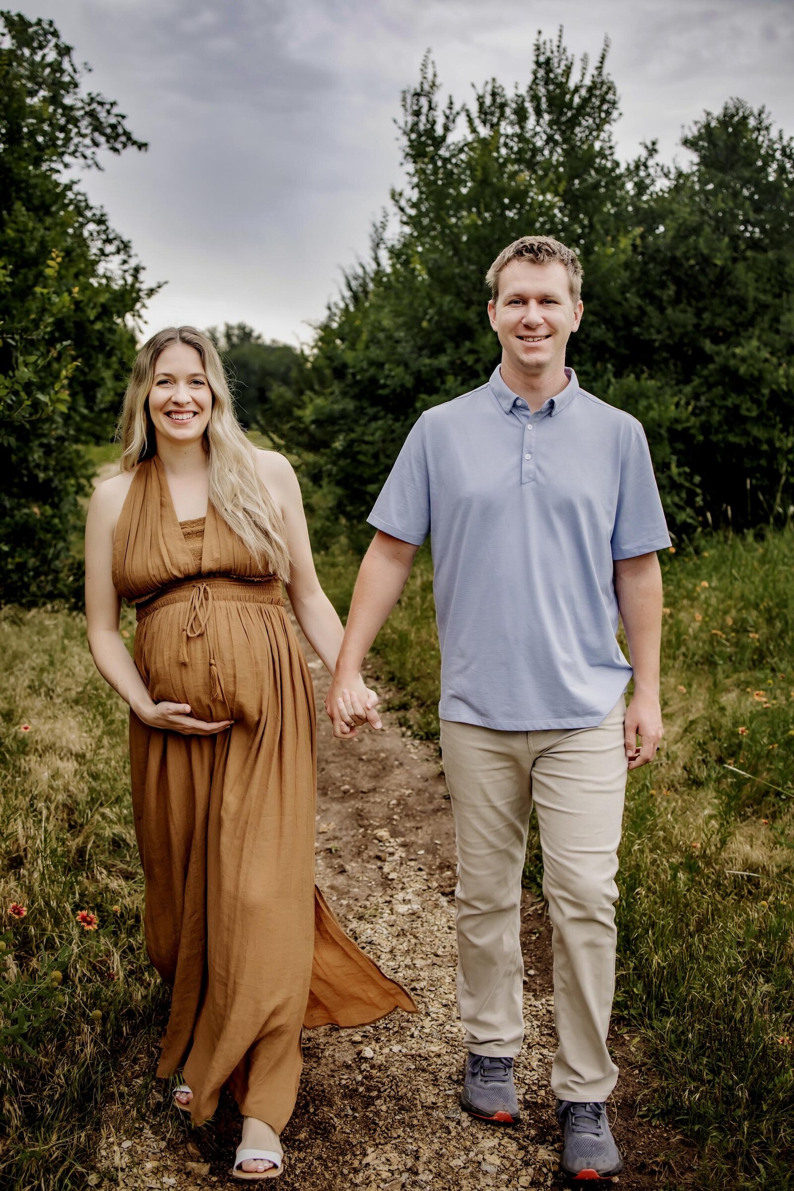 husband and wife hold hands at their maternity photography session in Grapevine Texas.
