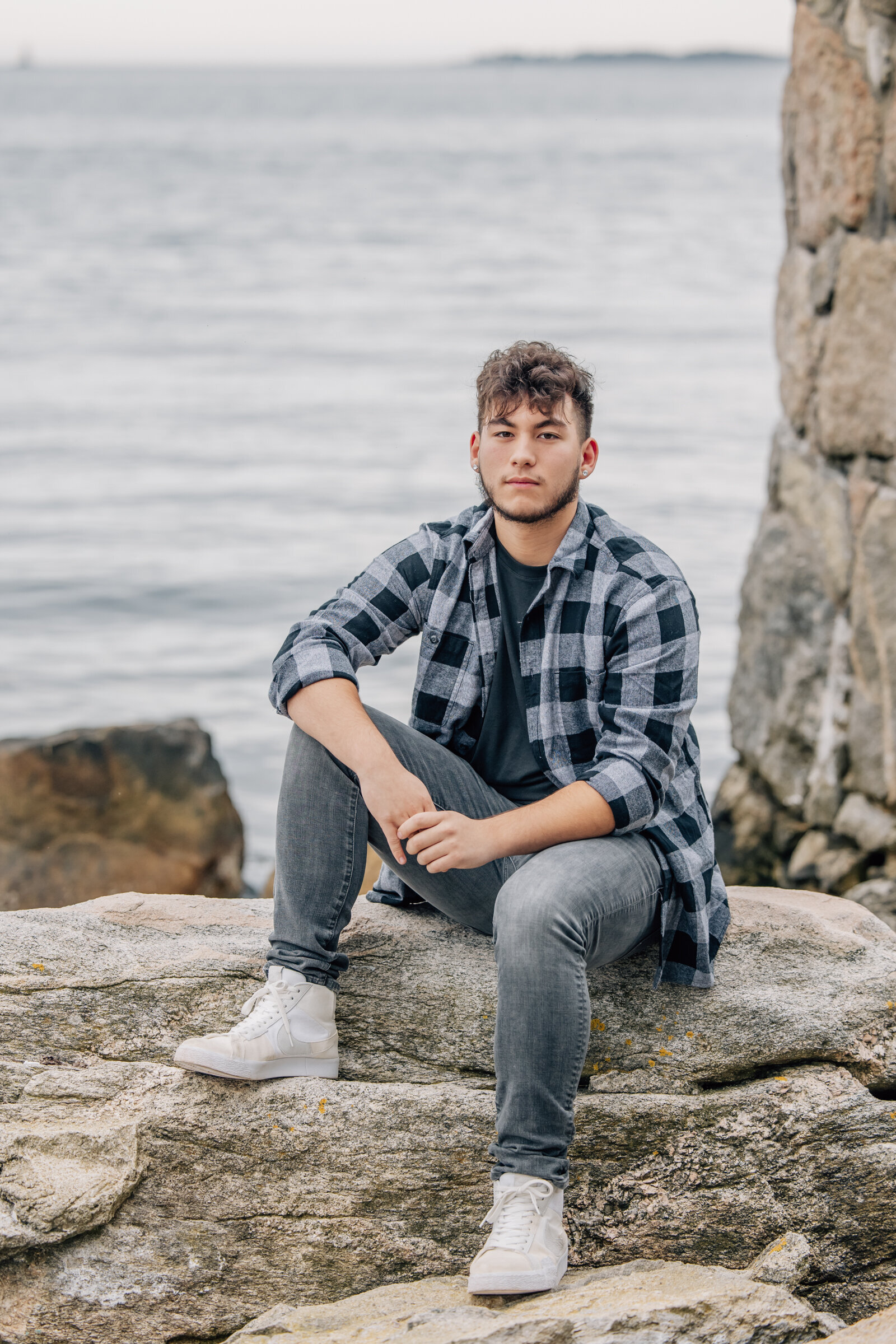 high school senior boy with dark hair looking at camera in front of water at ender's island in connecticut