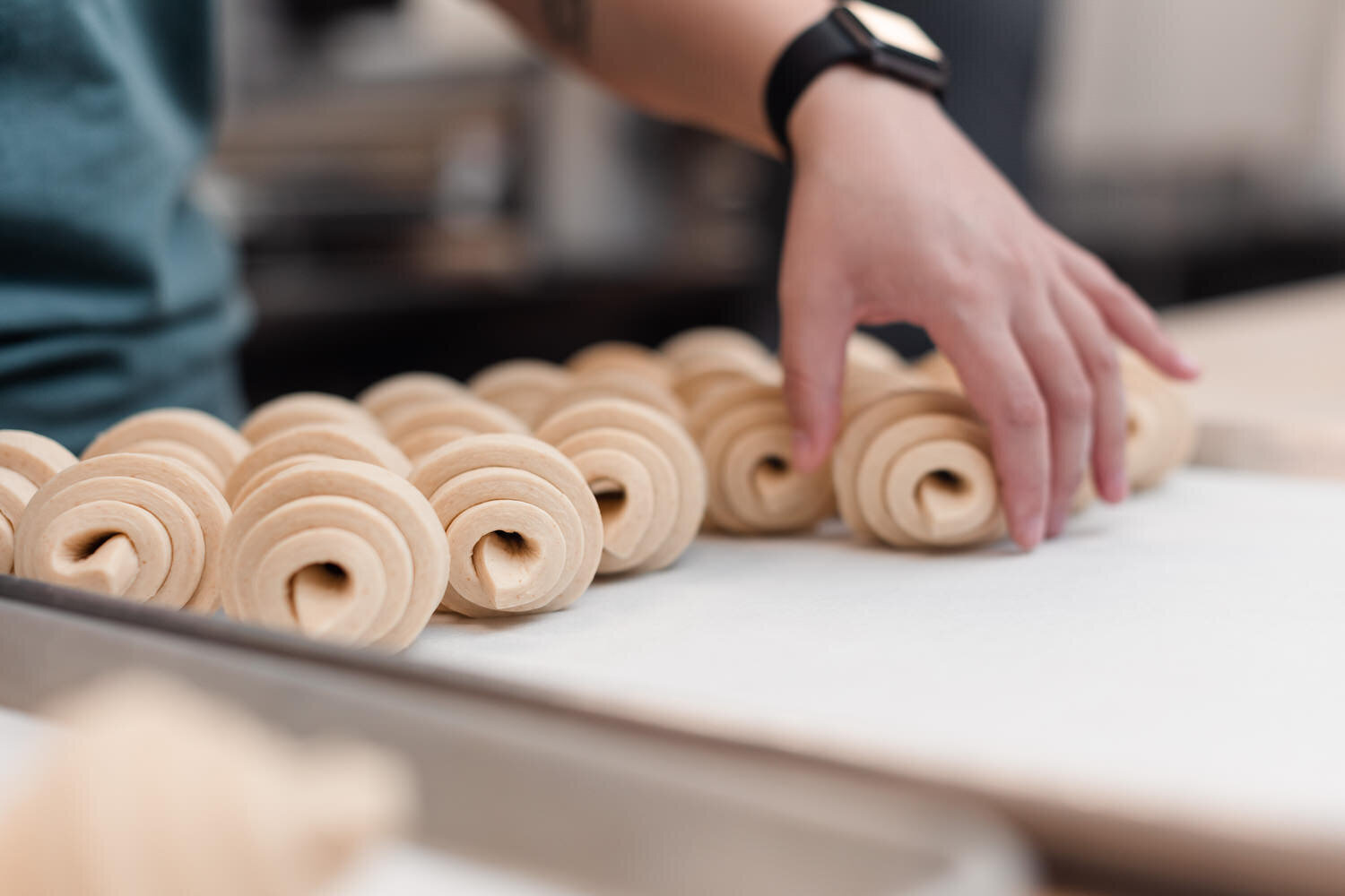 hands placing rolled croissant dough on a pan