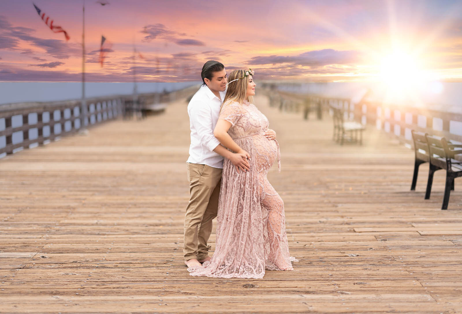 Woman and her husband standing on a pier for a maternity photoshoot